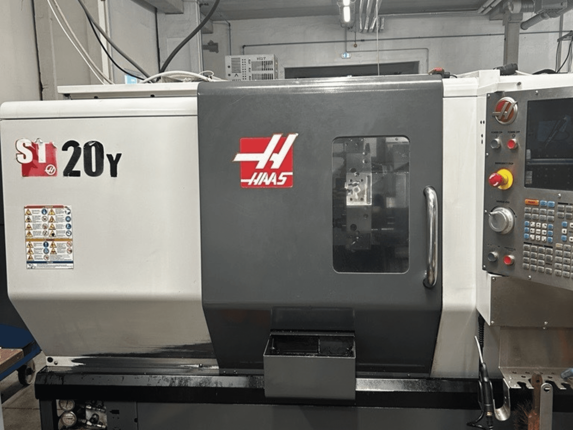 CNC soustruh Haas ST-20Y, pohled zepředu, zobrazující ovládací panel, bezpečnostní štítky a provozní okno.