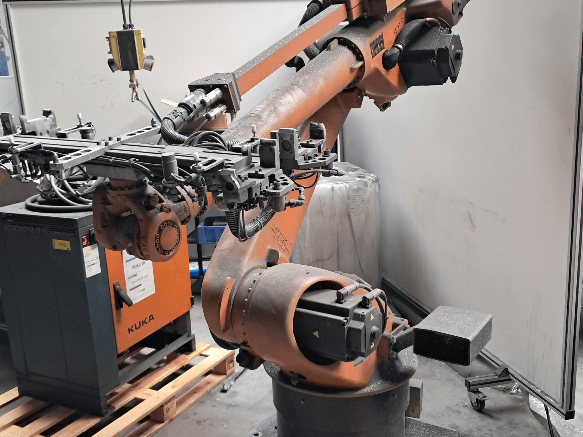 Robotické rameno KUKA KR 30L16-2 v bočním pohledu, s propracovaným koncovým efektorem a řídicími kabely, umístěné vedle řídicí skříně KUKA.