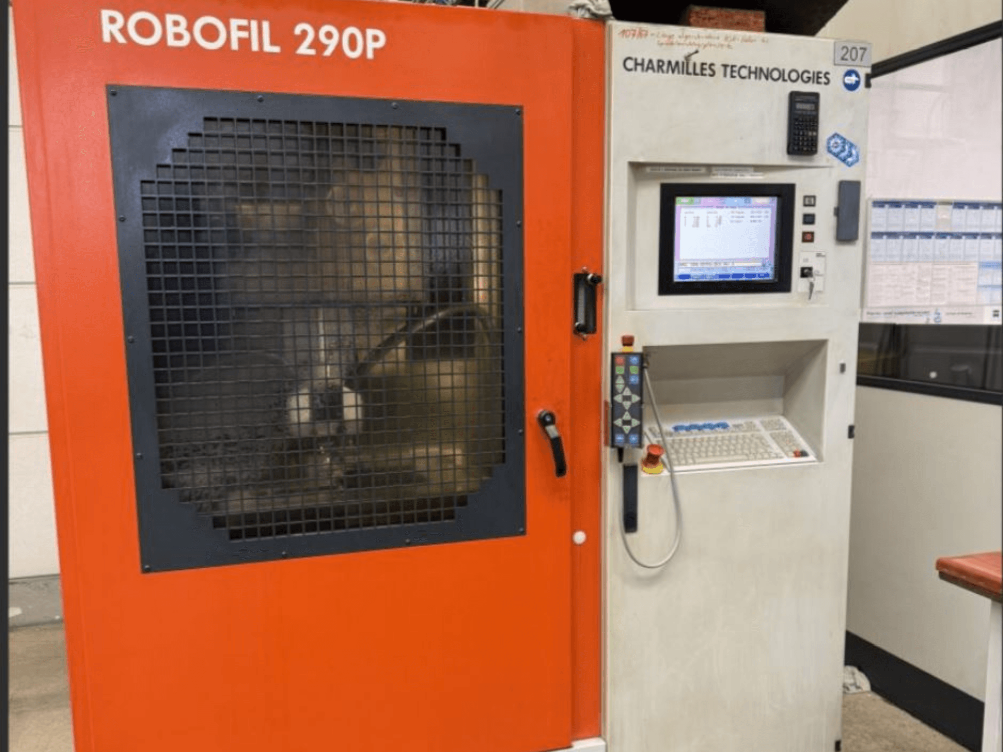 Pohled zepředu na drátový elektroerozivní stroj CHARMILLES TECHNOLOGIES Robofil 290P s ovládacím panelem a mřížkou chráněným pracovním prostorem.