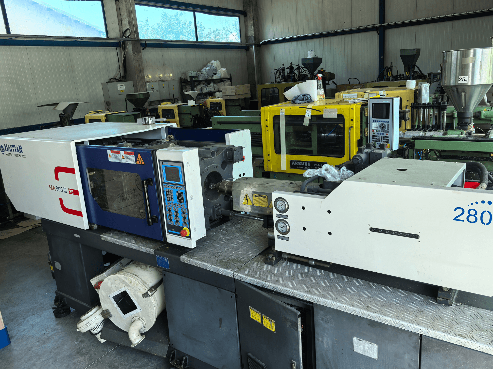 Hydraulický vstřikovací lis HAITIAN MA900ІІ, pohled zepředu, s ovládacím panelem a viditelnými technickými součástmi.