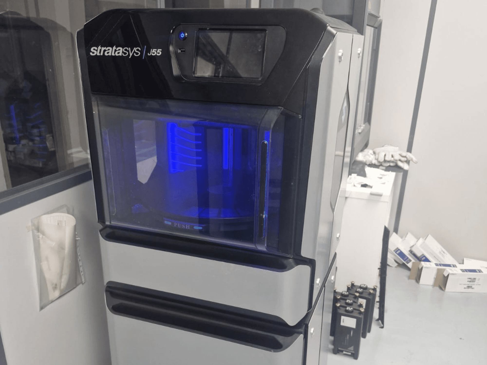 Plastová 3D tiskárna Stratasys J55 Prime v bočním pohledu, který ukazuje její elegantní design a osvětlený tiskový prostor.