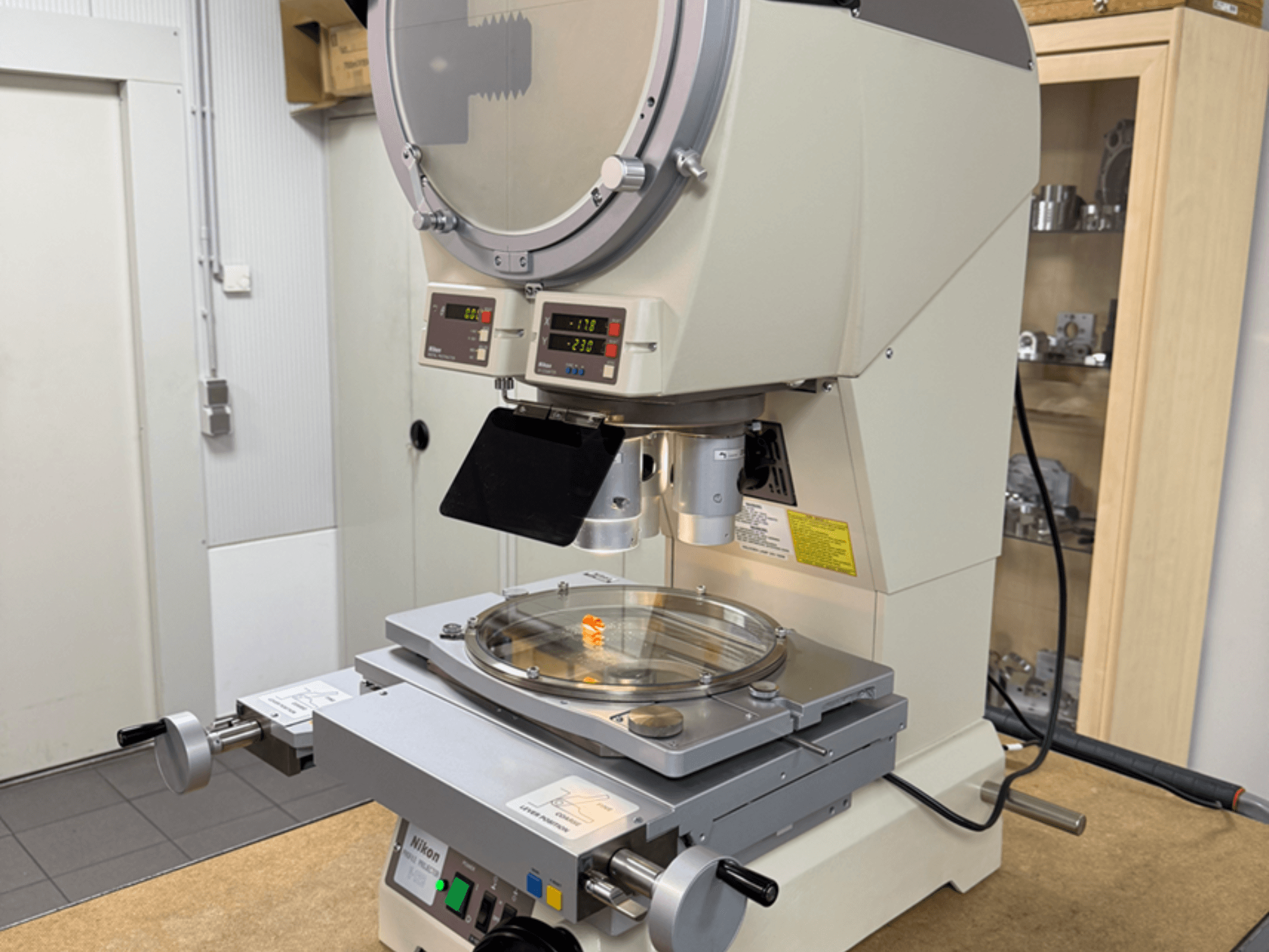 Model mikroskopu Nikon z čelního pohledu s digitálními displeji, nastavitelným stolkem a kruhovou skleněnou deskou.