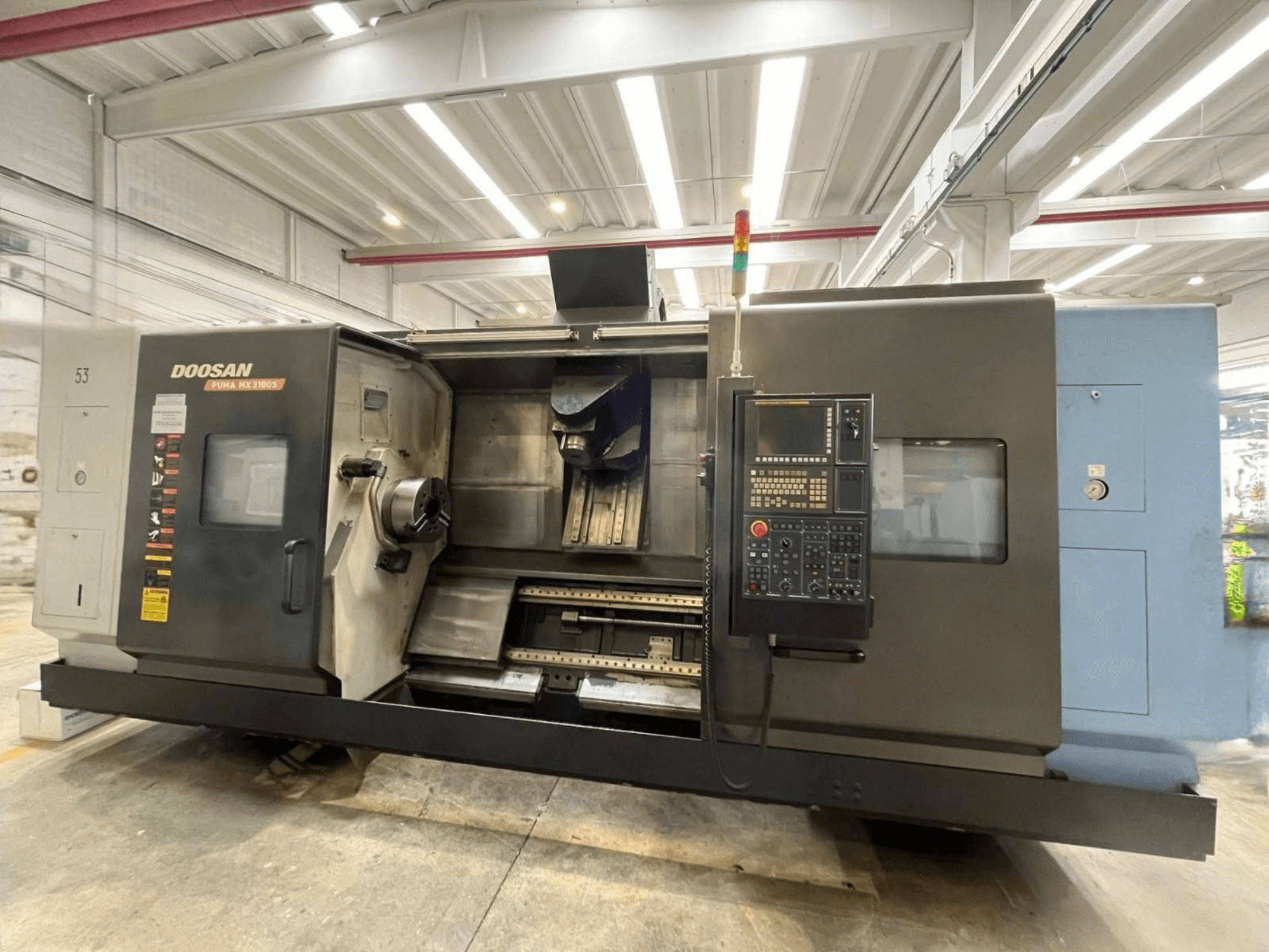 Pohled zepředu na horizontální soustruh DOOSAN PUMA MX3100 s ovládacím panelem a viditelnou oblastí vřetena a držáku nástroje.