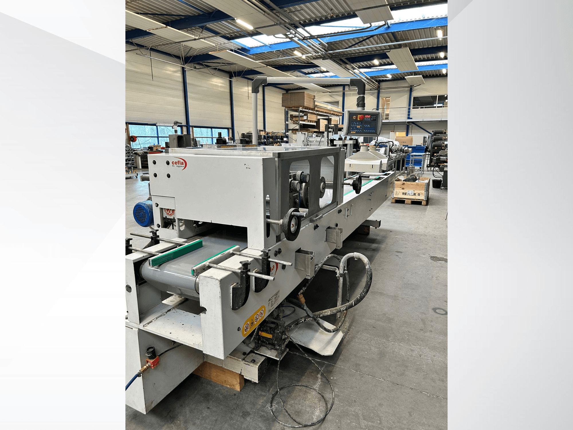 Pohled zepředu na stroj na zpracování dřeva CEFLA Smartparquet MRF-2VS/300, na kterém je vidět ovládací panel a dopravník se zelenými válečky.