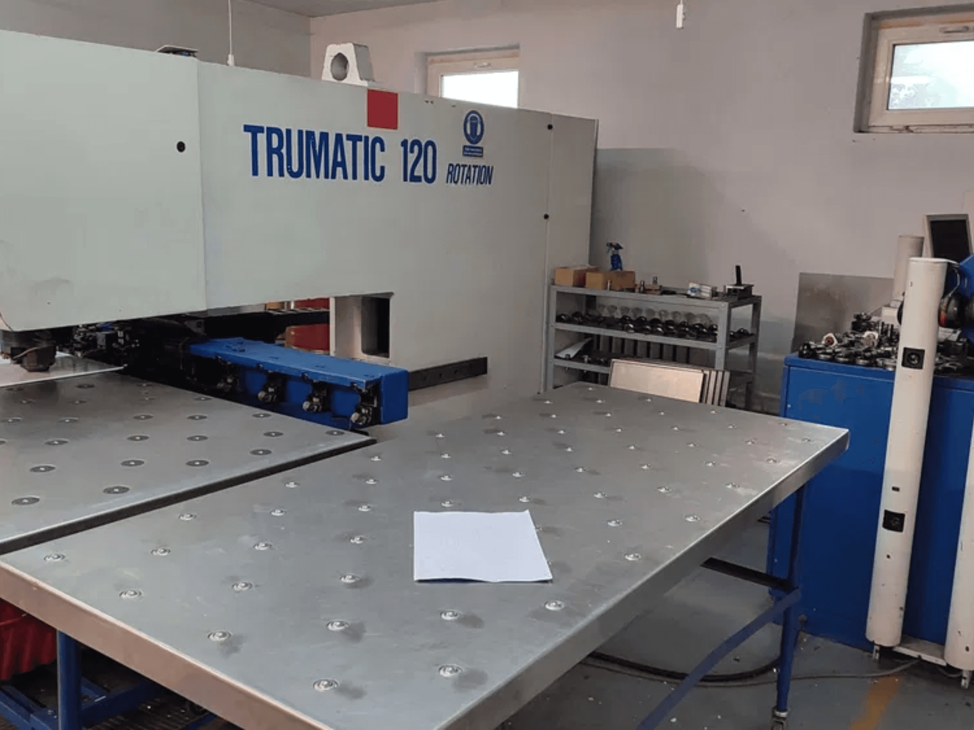 CNC děrovací stroj TRUMPF TRUMATIC 120R při pohledu zepředu, s kovovým stolem s děrovanými otvory a prázdným plechem.