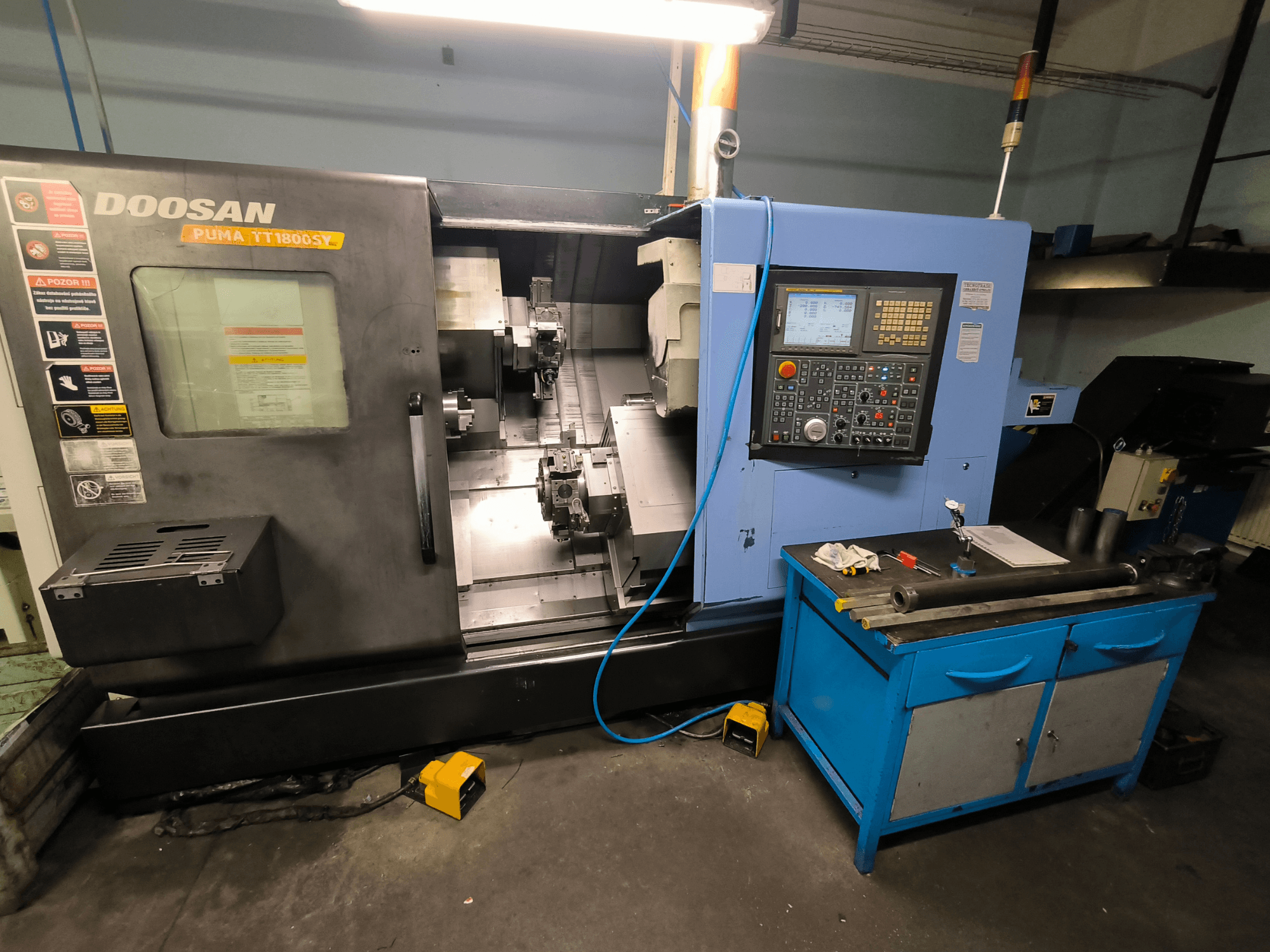 CNC soustruh Doosan Puma TT1800SY, pohled zepředu, zobrazující ovládací panel, pracovní plochu s nástroji a součásti stroje.
