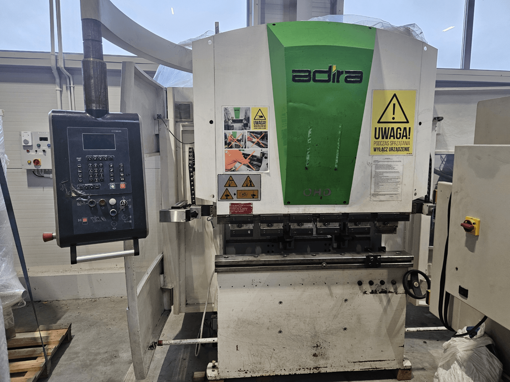 Stroj Adira OHD při pohledu zepředu, s ovládacím panelem, bezpečnostními upozorněními a provozními tlačítky.