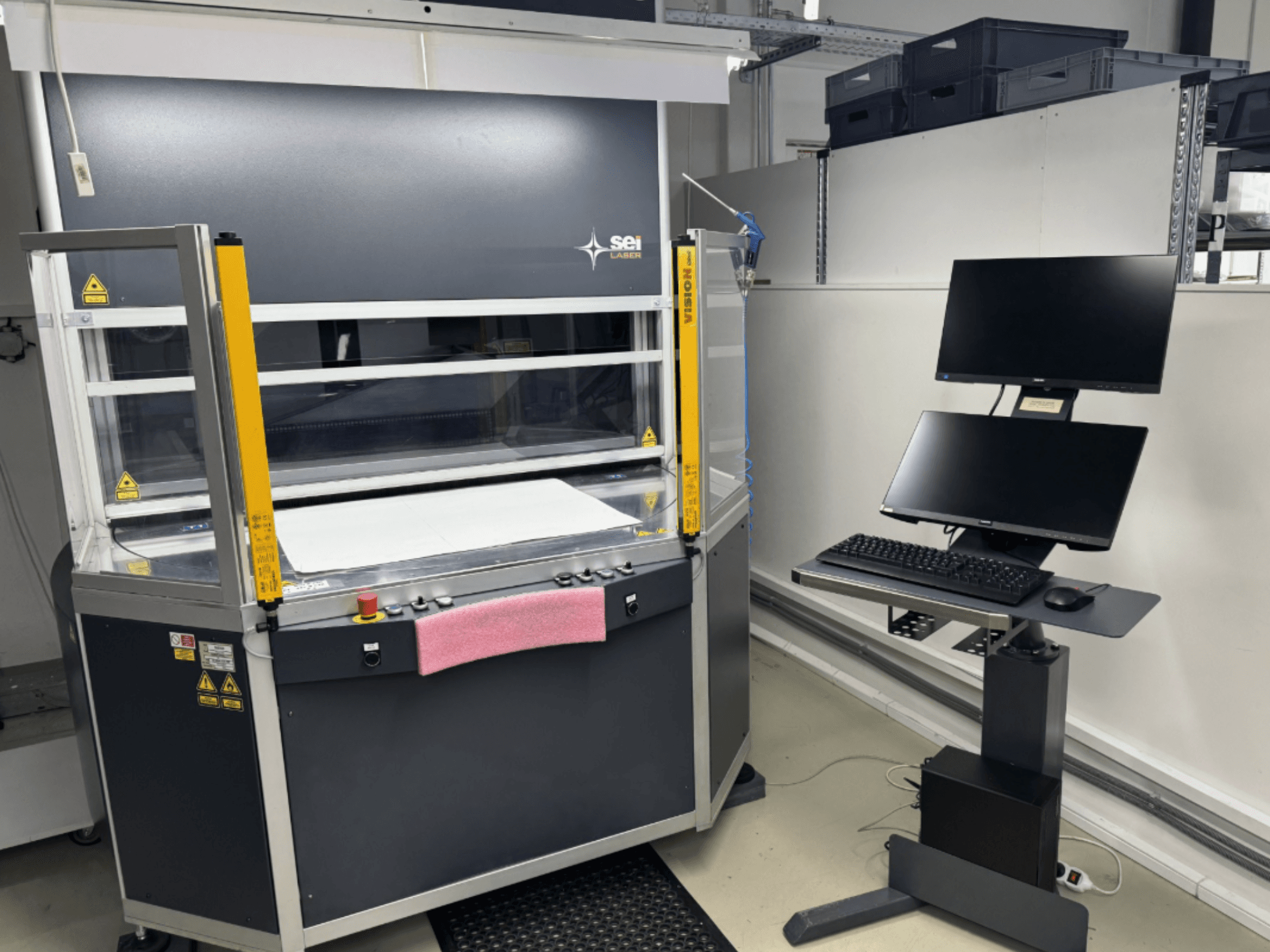 Laserový řezací stroj SEI Laser INFINITY 5070 V300 s CO₂ laserem – pohled zepředu, s ovládacím panelem a připojenou monitorovací stanicí.