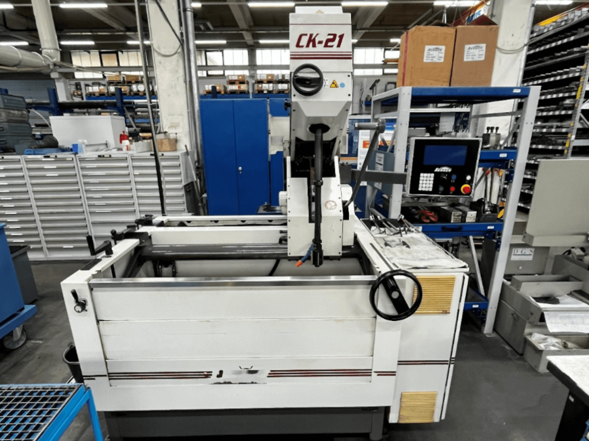 Vertikální honovací stroj Sunnen CK-21-CC v čelním pohledu, s ovládacími prvky, honovacím prostorem a podpůrným zařízením v pozadí.