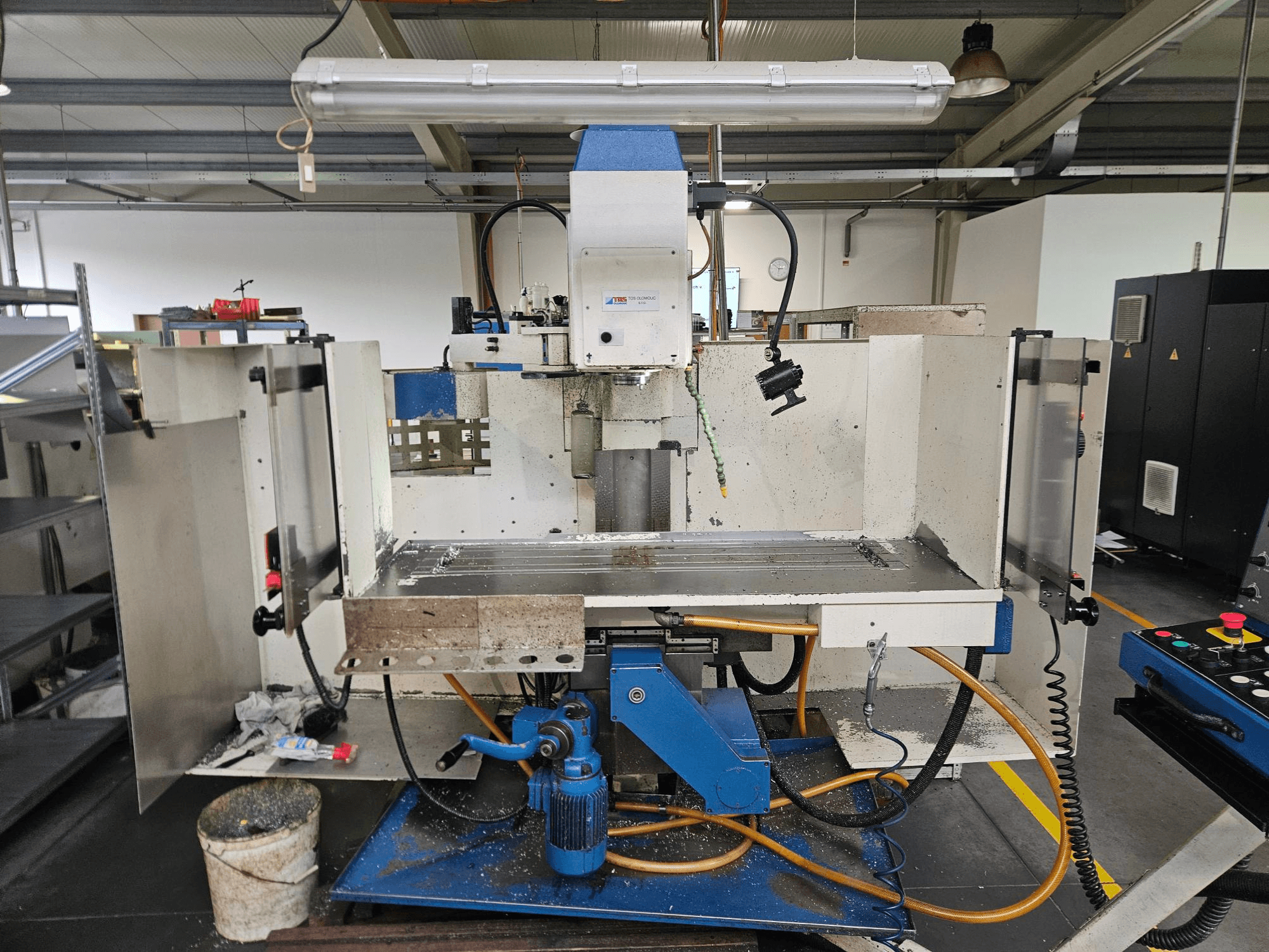 TOS Olomouc FV30 CNC Vertikální obráběcí centrum v dílně, čelní pohled ukazuje ovládací panel, pracovní stůl a chladicí systém.