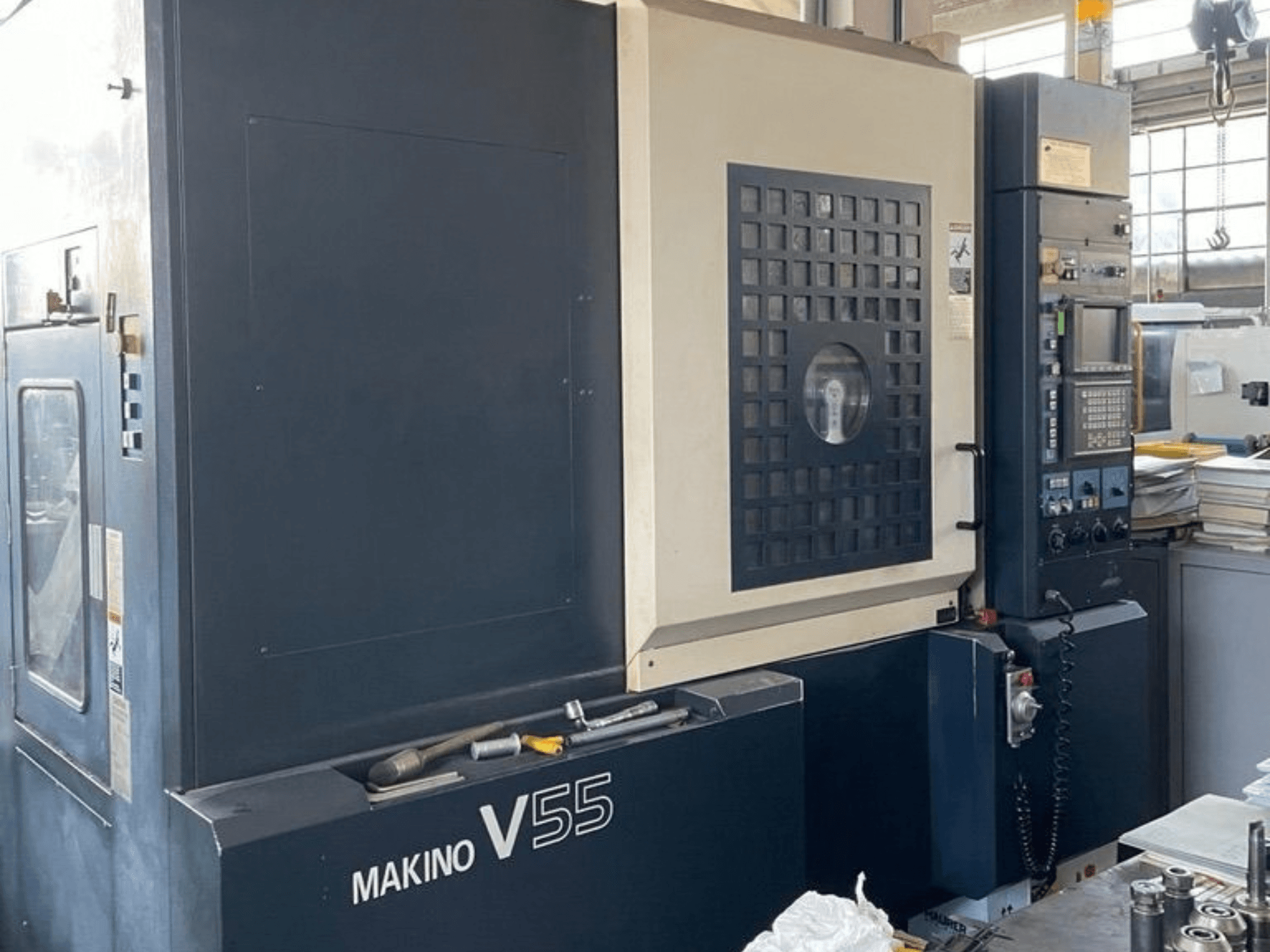 Vertikální obráběcí centrum Makino V55-A15, pohled zepředu znázorňující ovládací panel, robustní konstrukci a uspořádání pracovního prostoru.