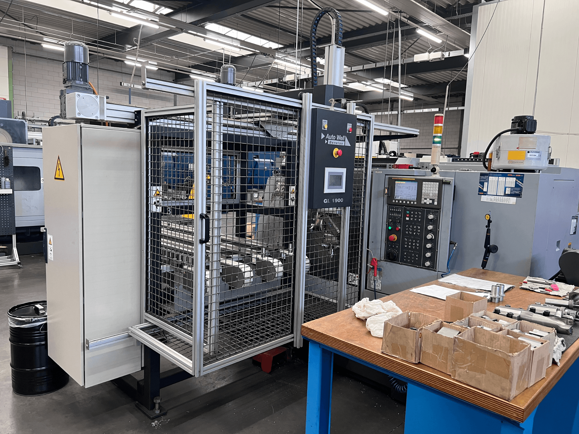 Pohled zepředu na stroj Auto Weld GL 1900 s ovládacím panelem, bezpečnostním krytem a okolními nástroji na pracovním stole.