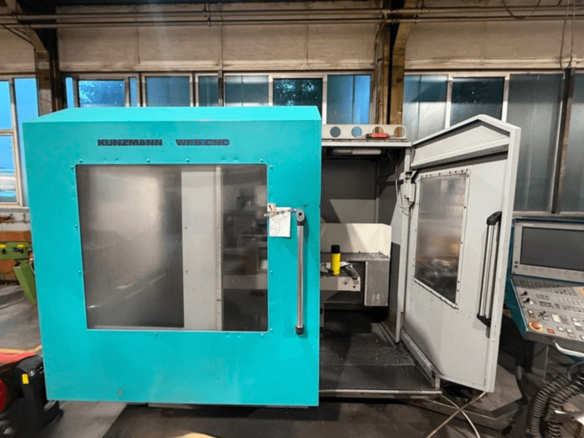 CNC vertikální obráběcí centrum KUNZMANN WF9, pohled zepředu s otevřenými dveřmi, ukazuje interiér a ovládací panel.