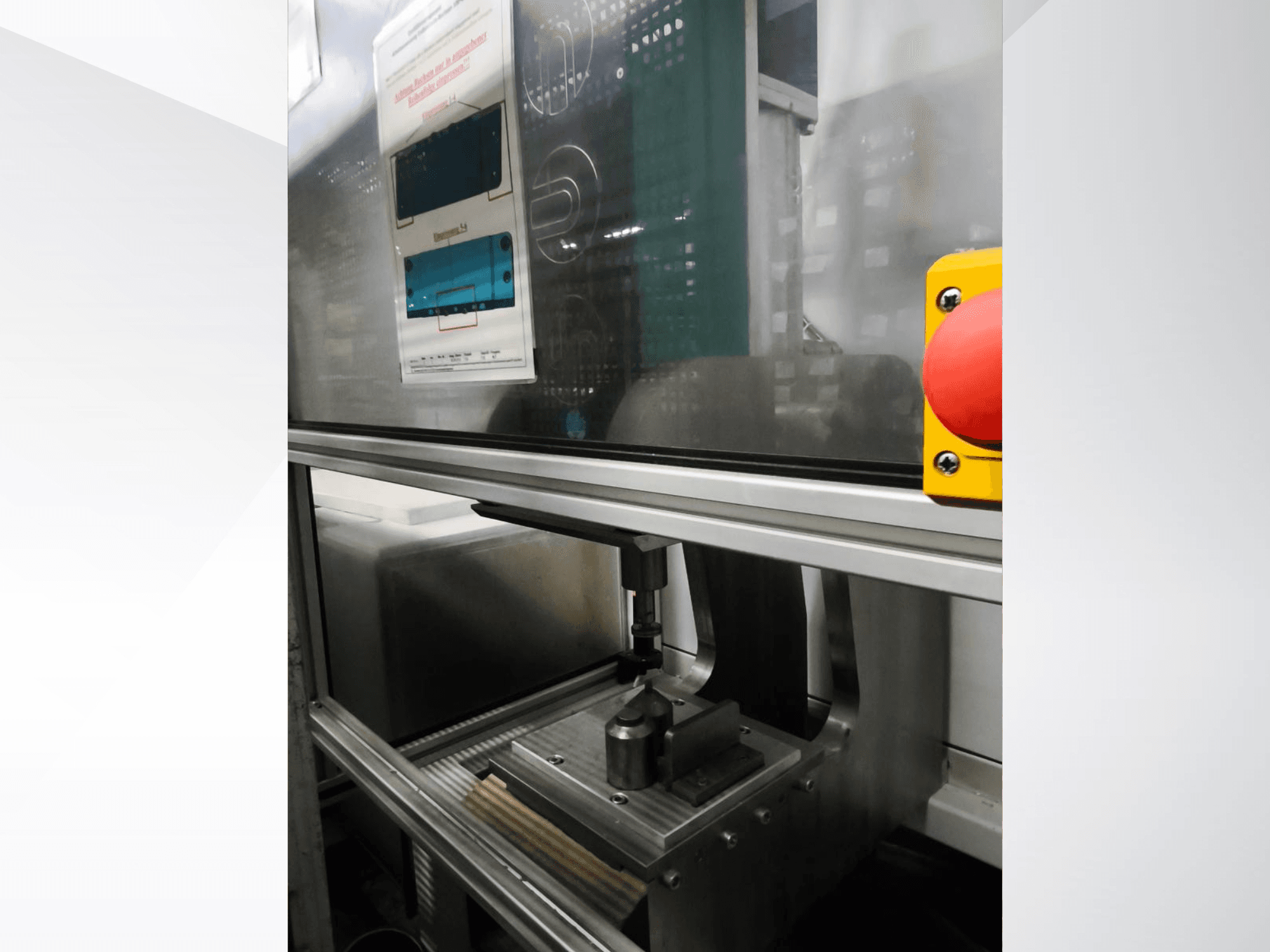 Pohled zepředu na obráběcí stroj EMS Automation Buchsenpresse, na kterém je vidět lisovací mechanismus a bezpečnostní tlačítko.