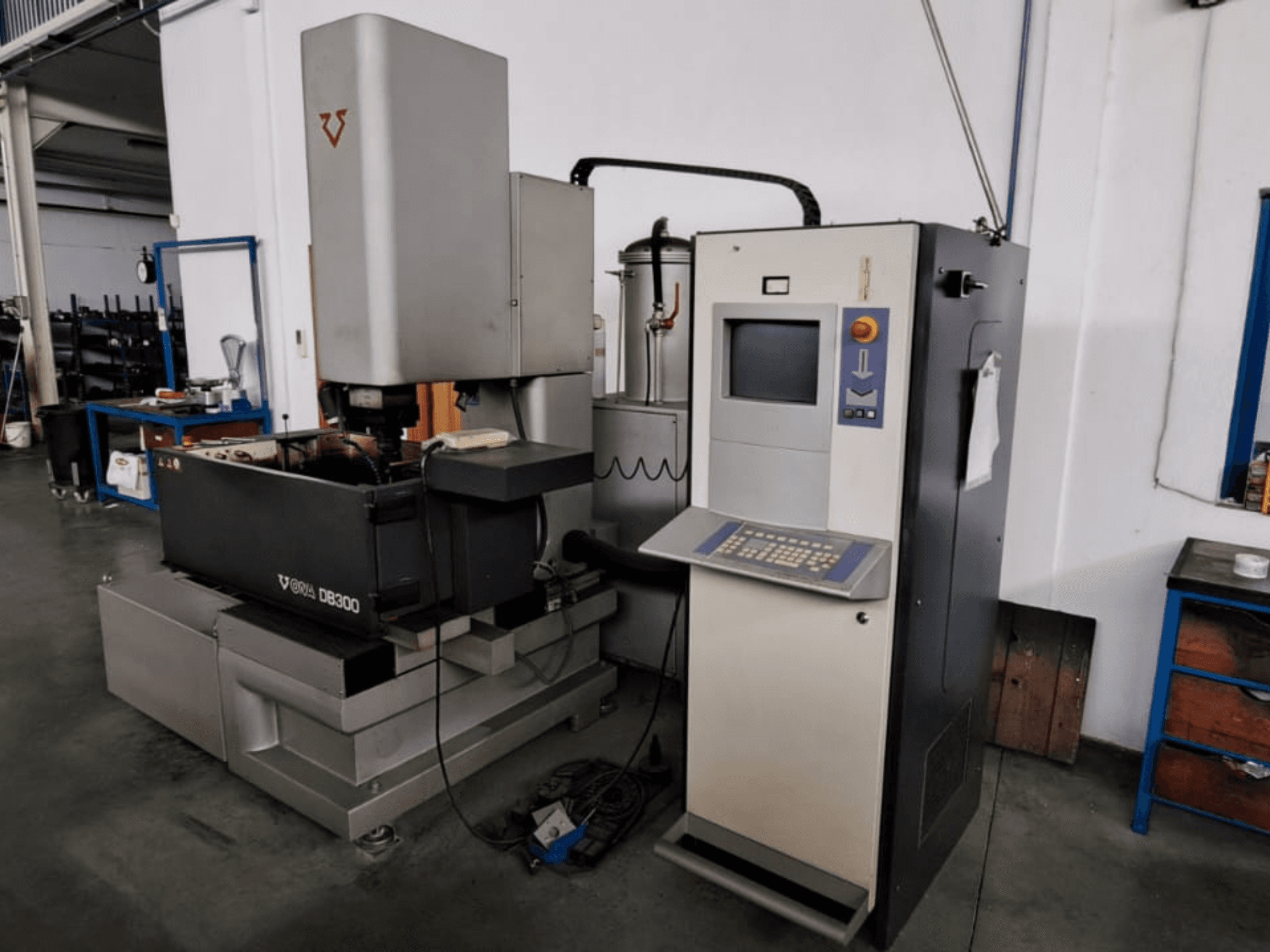 Hloubicí elektroerozivní stroj ONA DB300, pohled zepředu; ovládací panel, držák obrobku a prvky průmyslového designu.