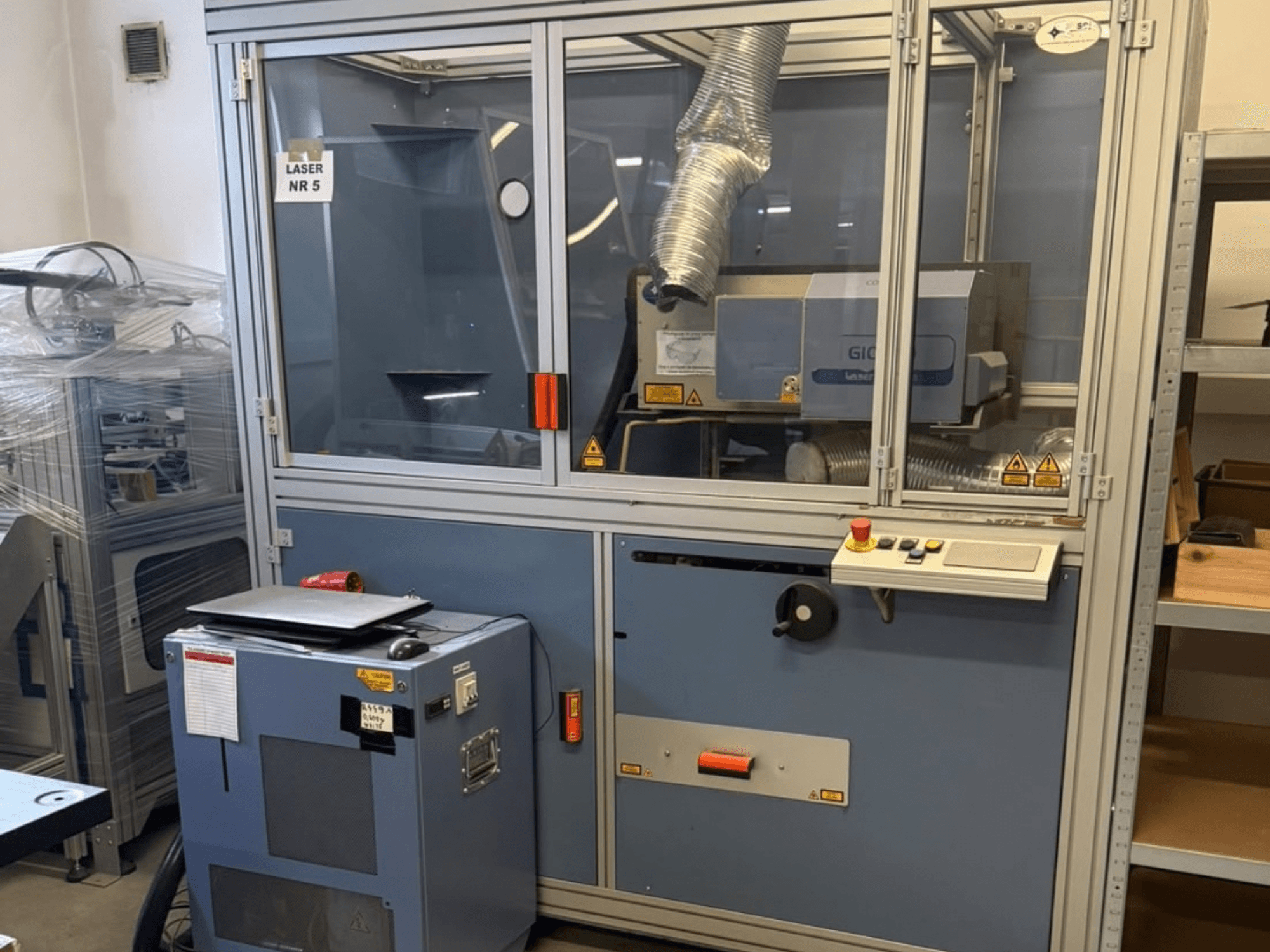 CO₂ laserový řezací stroj SEI Laser PAPER BLASTER 02, pohled zepředu, s ovládacím panelem a odvětrávacím potrubím.