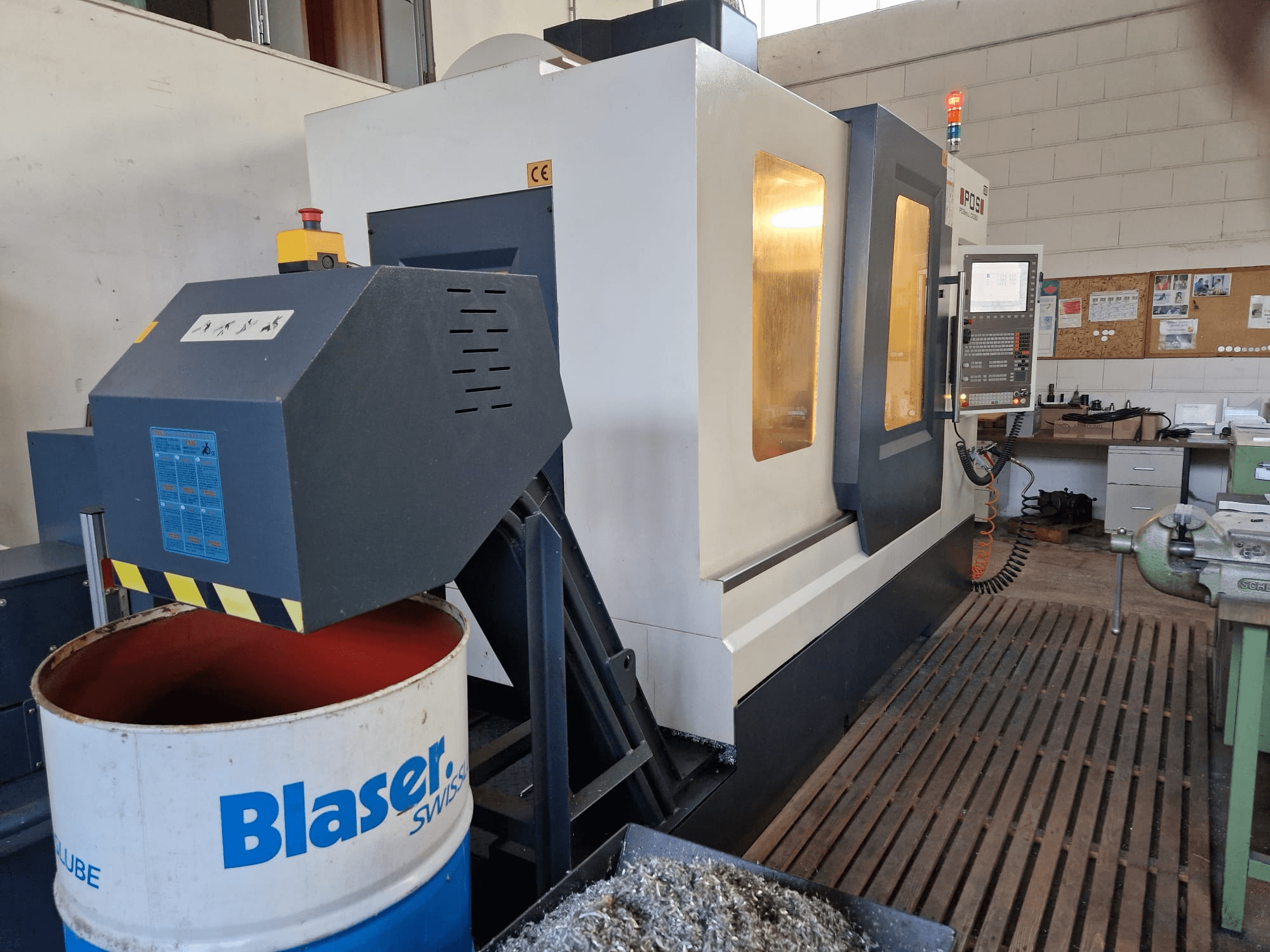 Pohled zepředu na vertikální obráběcí centrum POSmill C 1050, s viditelným chladicím systémem nad bubnem Blaser a ovládacím panelem.