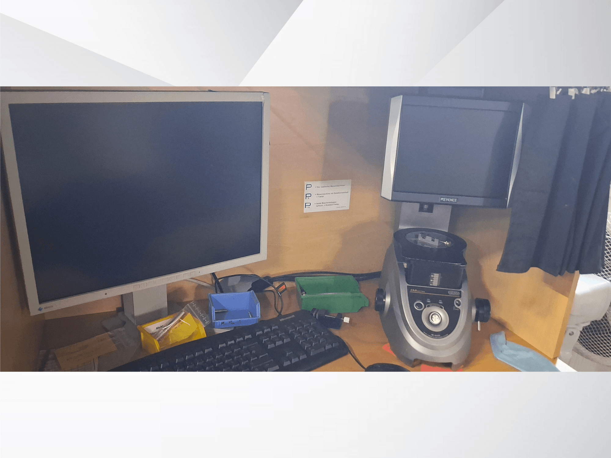 Počítačový monitor s klávesnicí, displej značky PEVA a šedý laboratorní přístroj na dřevěném stole s různými zásobníky a papíry.