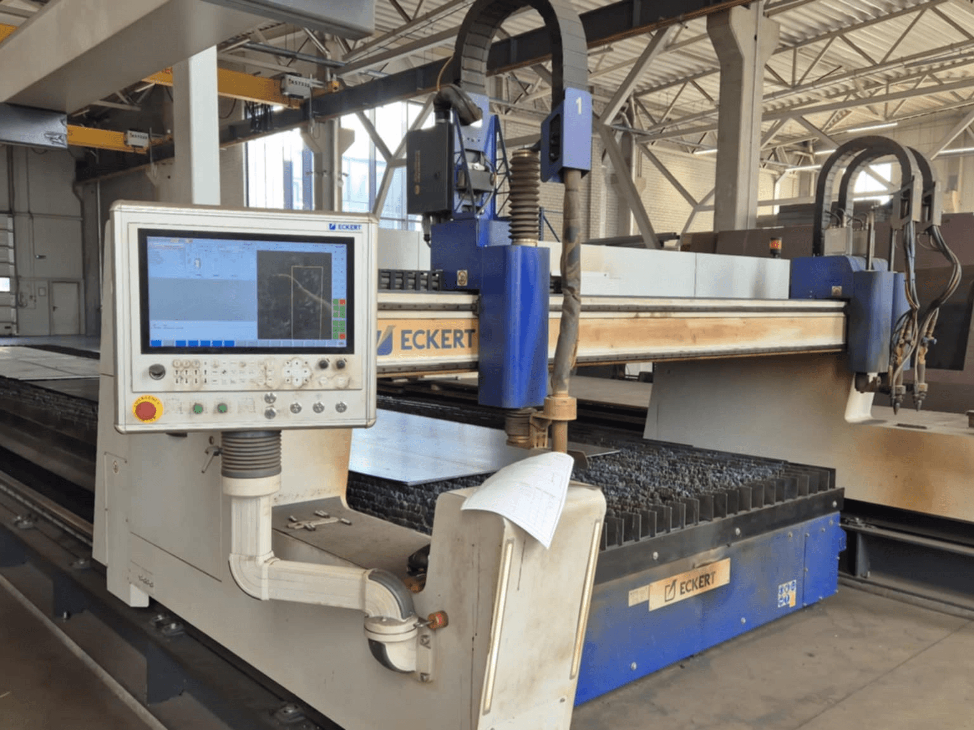 Ovládací panel CNC řezacího stroje ECKERT v čelním pohledu, s dotykovým displejem a různými ovládacími tlačítky.