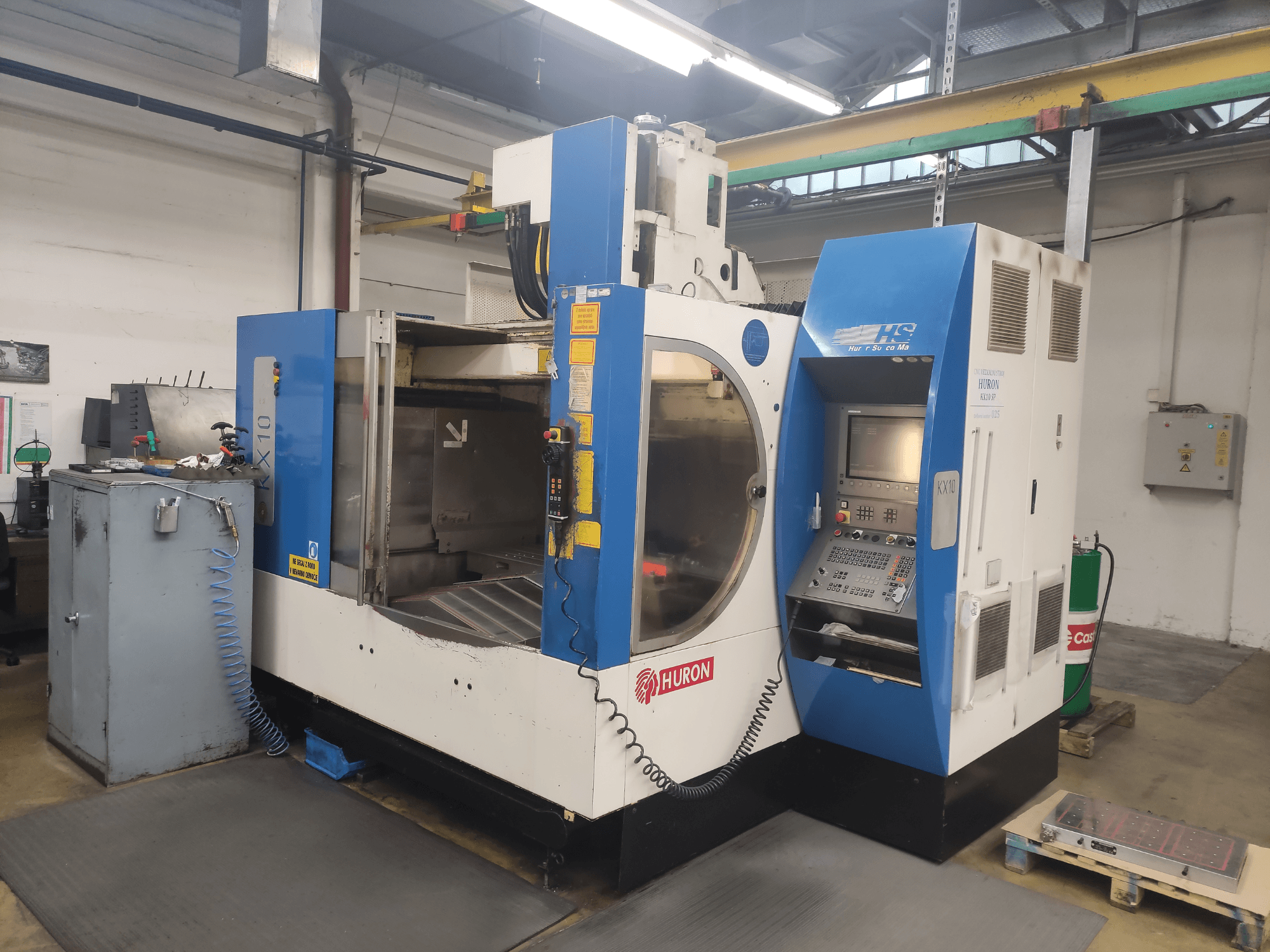 CNC stroj HURON KX10 v dílně, pohled zepředu, s ovládacím panelem a velkým otvorem pro obrábění.