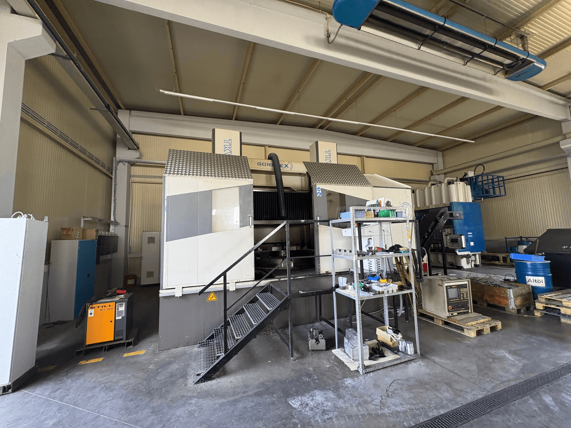 Průmyslové obráběcí zařízení se strojem GORAT X, pohled z boku; včetně nástrojů, ovládacího panelu a zařízení na policích.