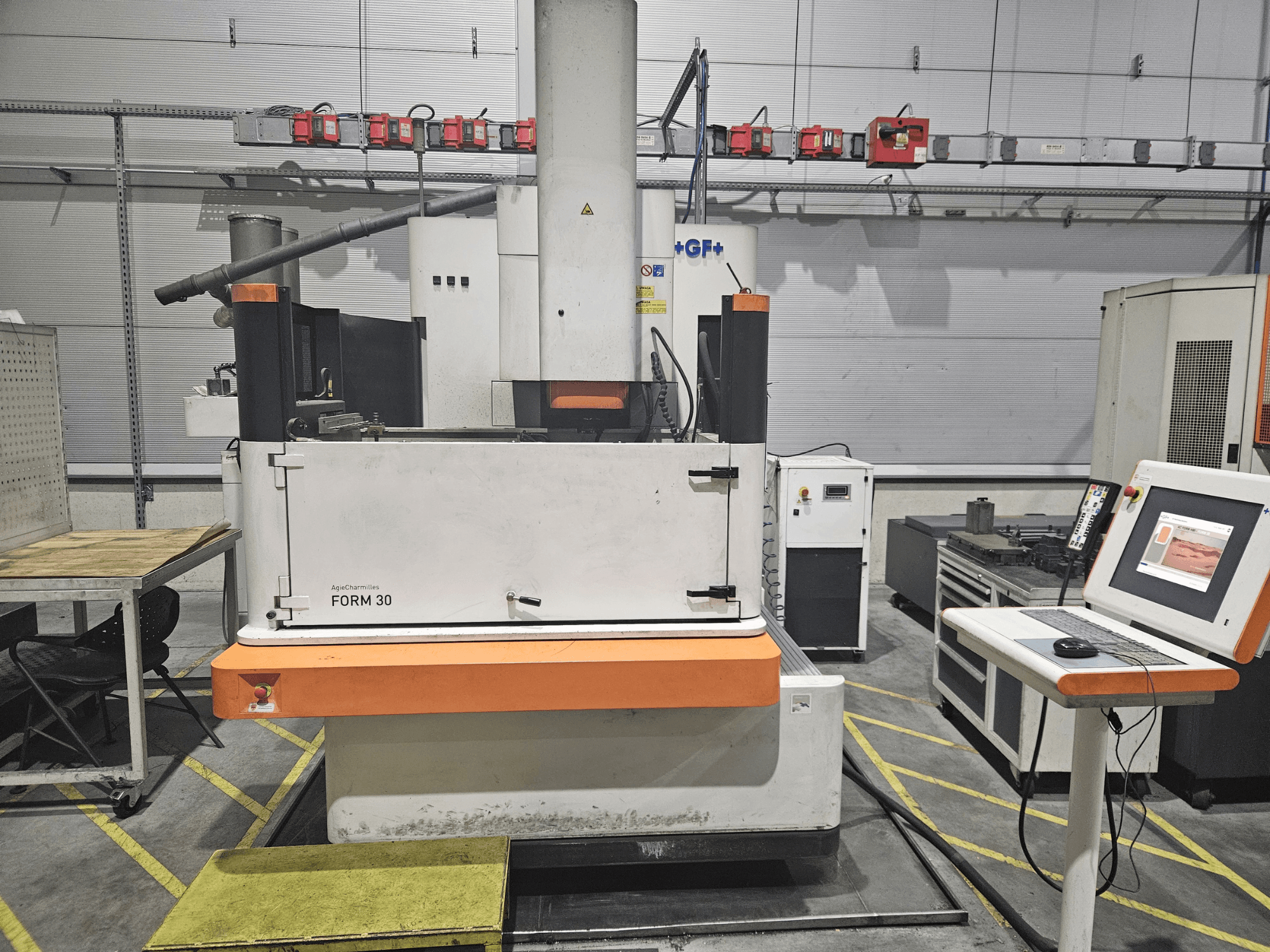 Stroj ApeqChemicals FORM 30 v dílně, pohled zepředu s ovládacím panelem a pracovním stolem po straně.