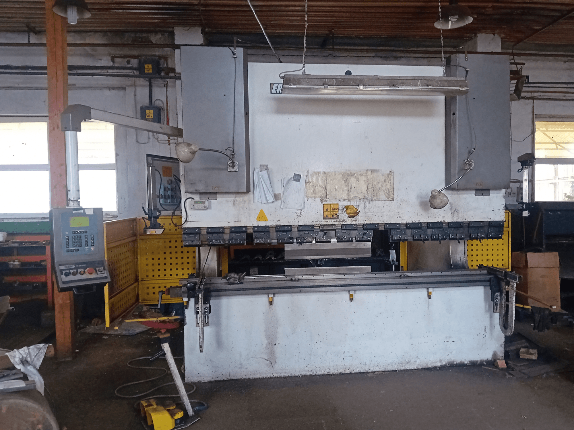 Hydraulický lis ERMAK CNC HAP 3100x300 v čelním pohledu, s ovládacím panelem a pracovním stolem v dílně.