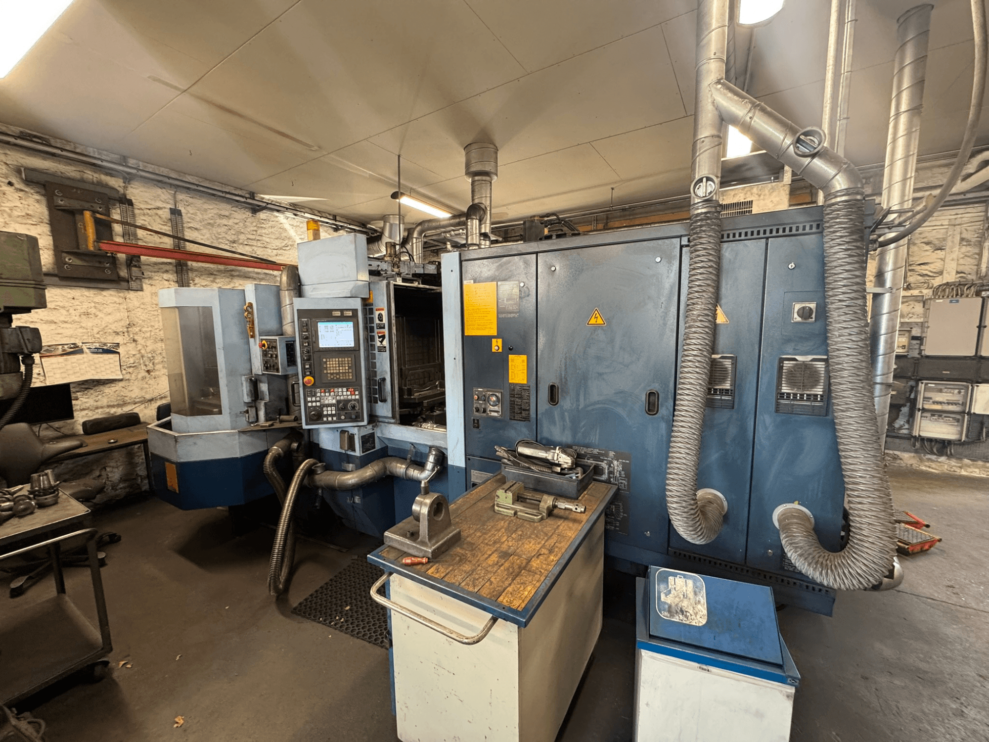 Horizontální obráběcí centrum Matsuura H.PLUS-300 v dílně, pohled zepředu, na kterém je vidět ovládací panel a pracovní stůl.