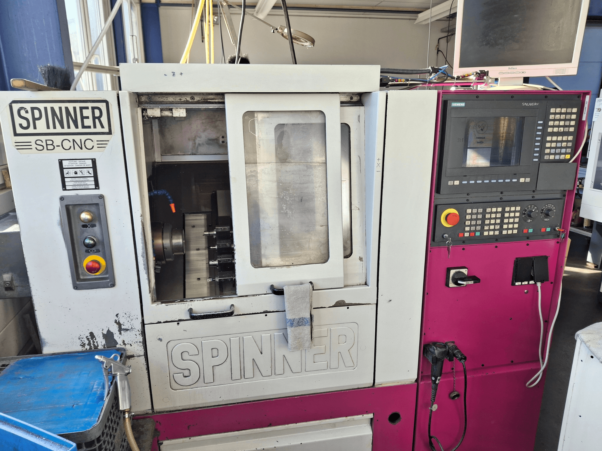 Horizontální soustruh SPINNER SB-CNC, čelní pohled zobrazující ovládací panel, držák nástrojů a provozní ukazatele.
