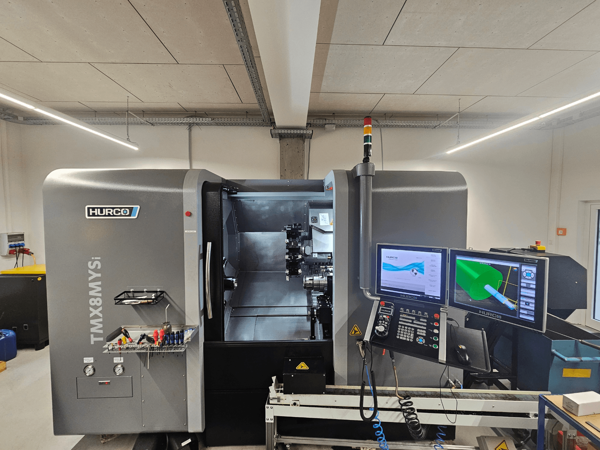 Soustružnické centrum Hurco TMX 8 MYSi v dílně, se dvěma monitory, ovládacím panelem a nářadím na boku.