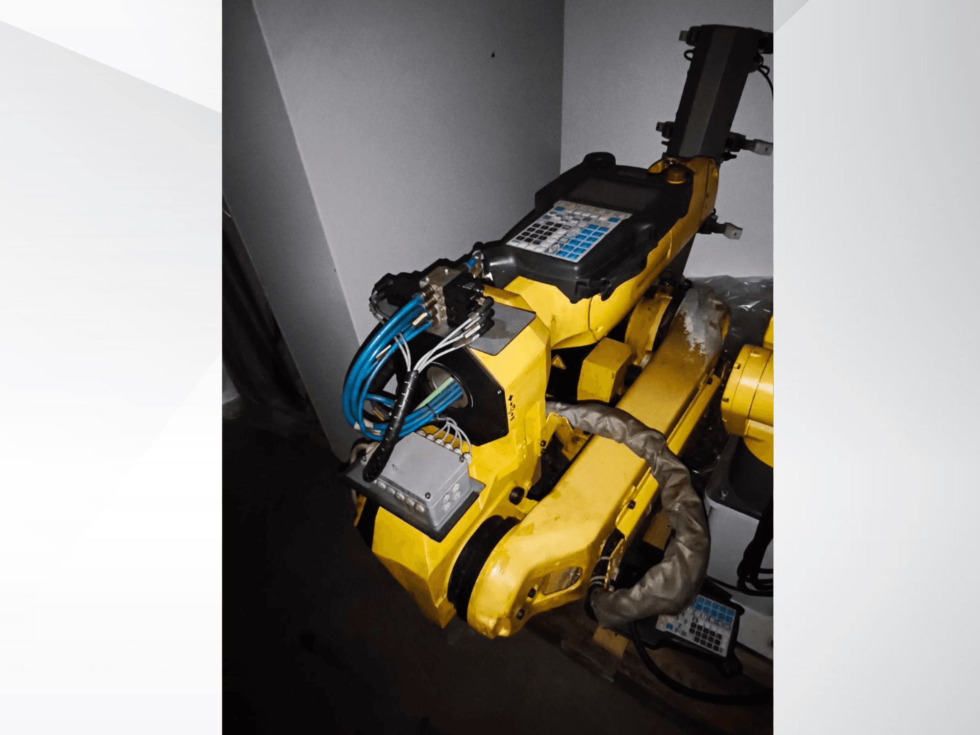 Robotické rameno FANUC M-20iA v bočním pohledu, na kterém je vidět žluté tělo, ovládací panel a připojená kabeláž.