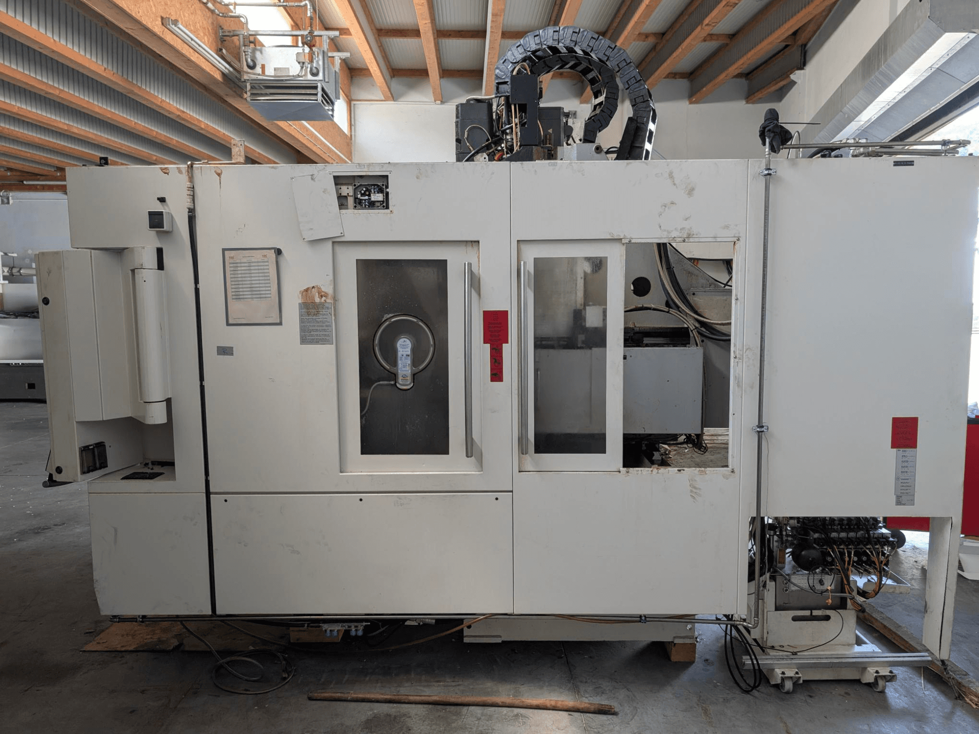 Vertikální obráběcí centrum STAMA MC 326, boční pohled zobrazující ovládací panel, prostor vřetena a různé štítky na stroji.