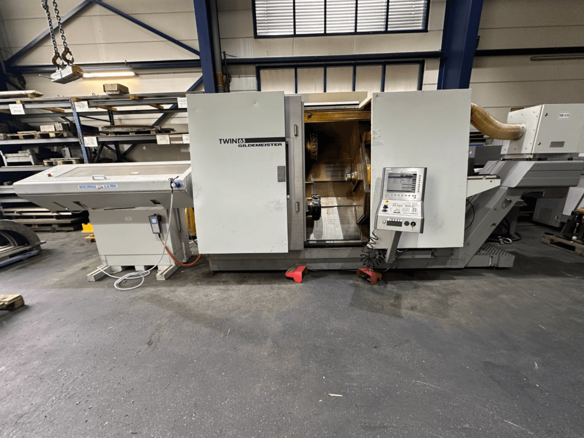 Horizontální soustruh Gildemeister TWIN 65, pohled zepředu; ovládací panel a viditelný interiér pro obrábění dílů.