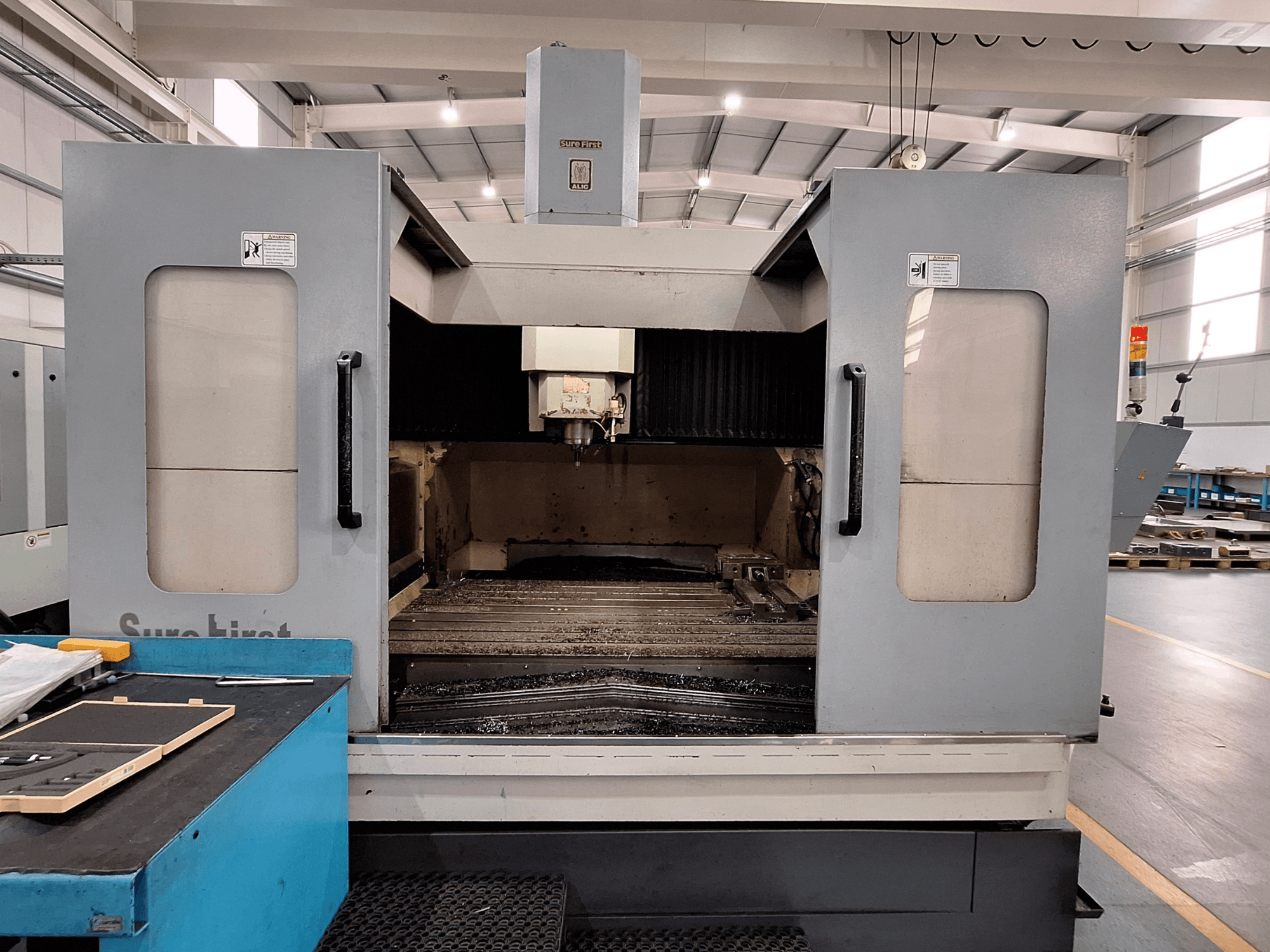 Vertikální obráběcí centrum Sure First QM-1836, čelní pohled na nástrojovou hlavu a prázdný pracovní prostor, moderní průmyslové prostředí.