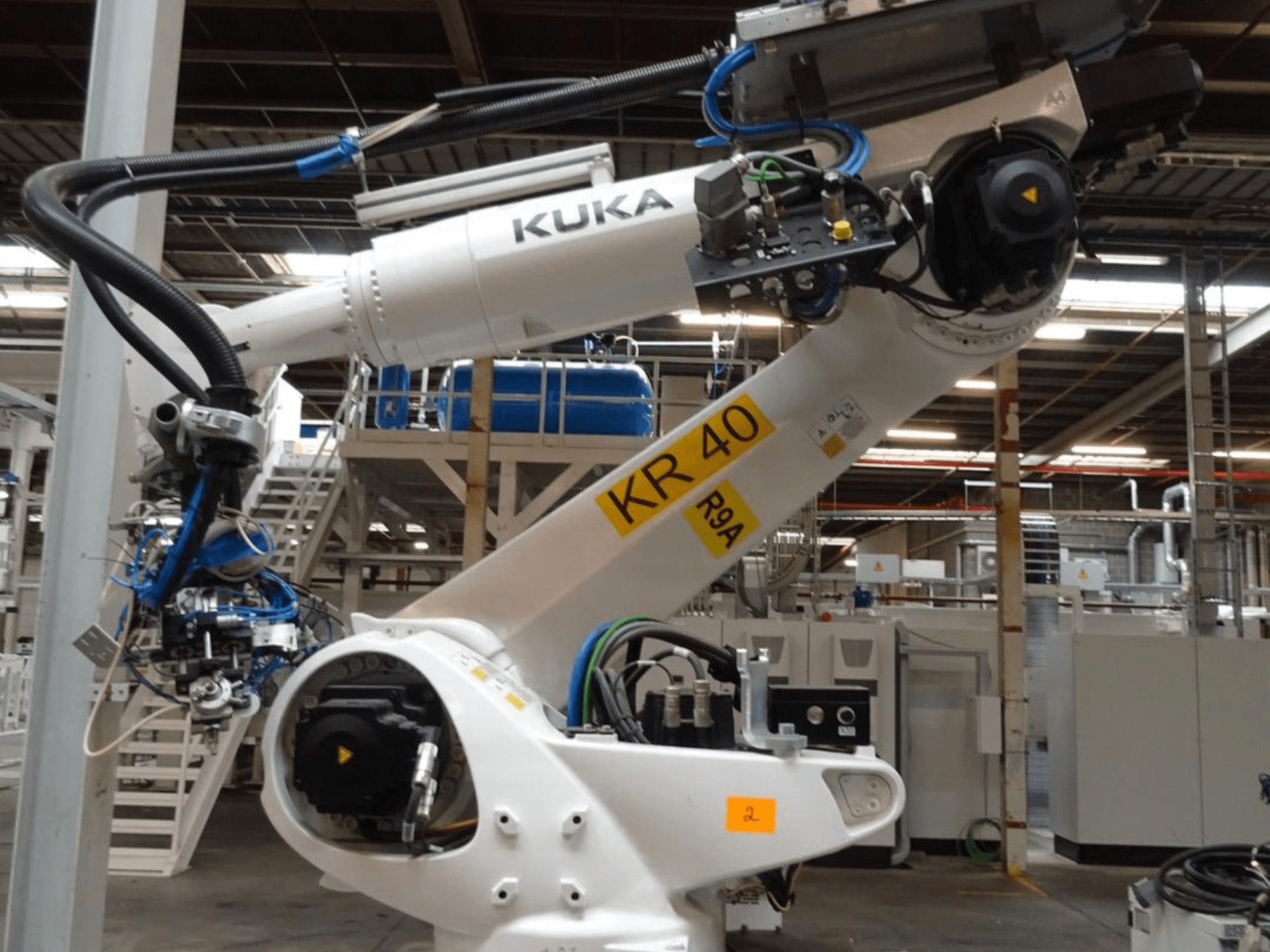 Robotické rameno KUKA KR 120 R3100-2 v bočním pohledu, na kterém je vidět ovládací panel a mechanické součásti, zasazené do průmyslového prostředí.