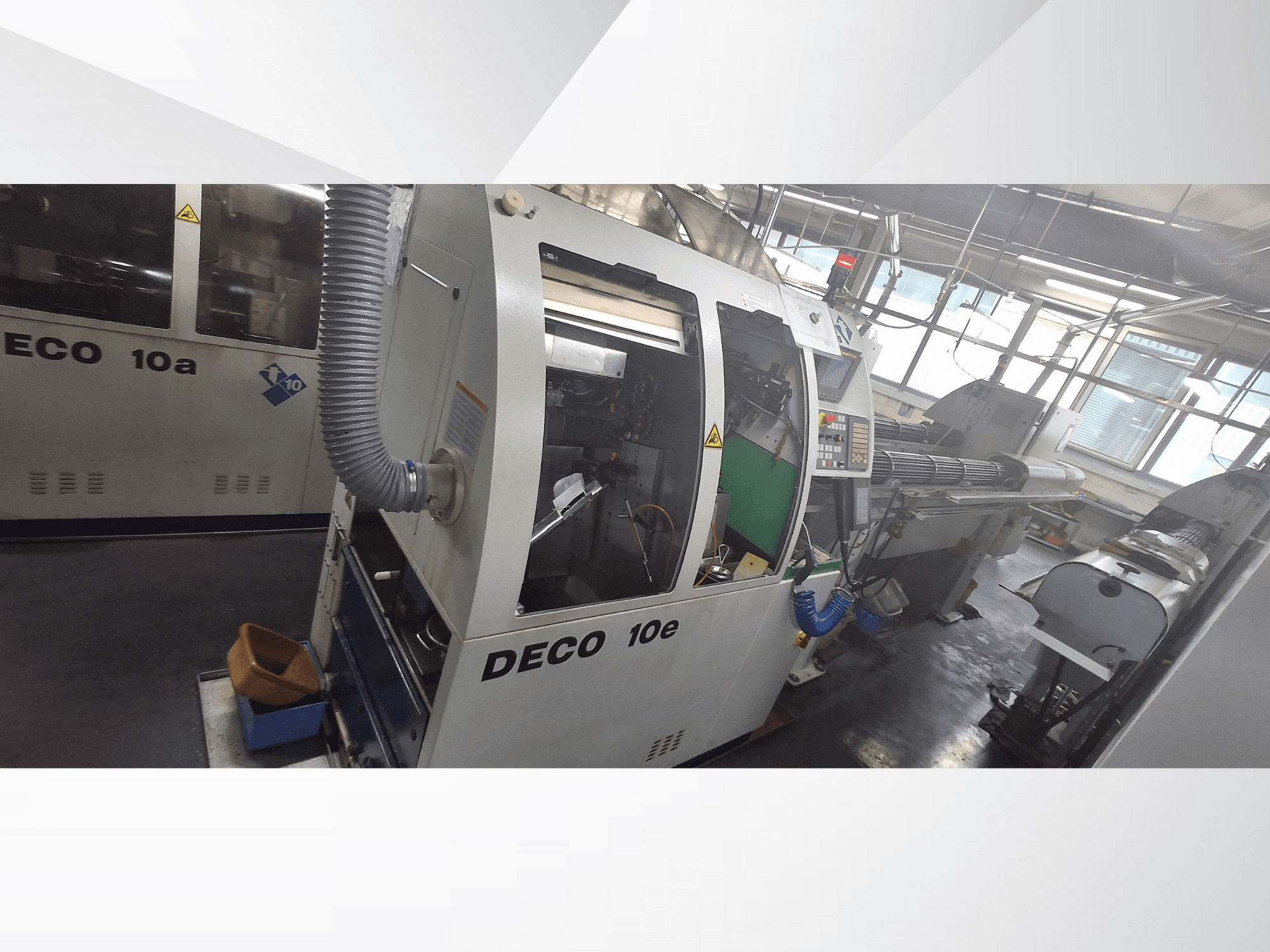 CNC stroj DECO 10e v bočním pohledu, s ovládacím panelem, zeleným interiérem a připojenou výfukovou hadicí.