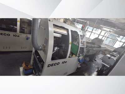 CNC stroj DECO 10e v bočním pohledu, s ovládacím panelem, zeleným interiérem a připojenou výfukovou hadicí.