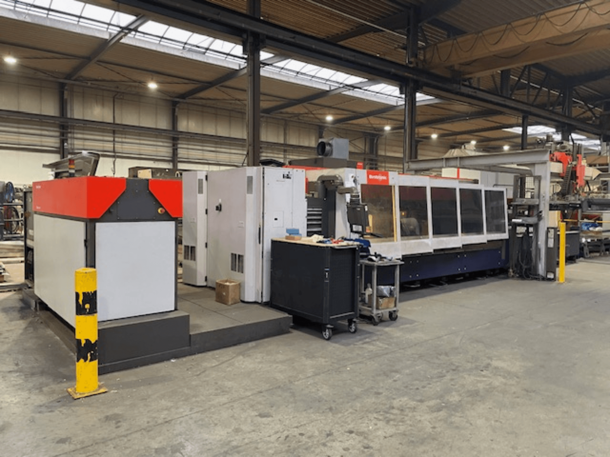 Laserový řezací stroj Bystronic BySpeed 3015 CO2, boční pohled v dílně, s výraznými červenými a šedými designovými prvky.