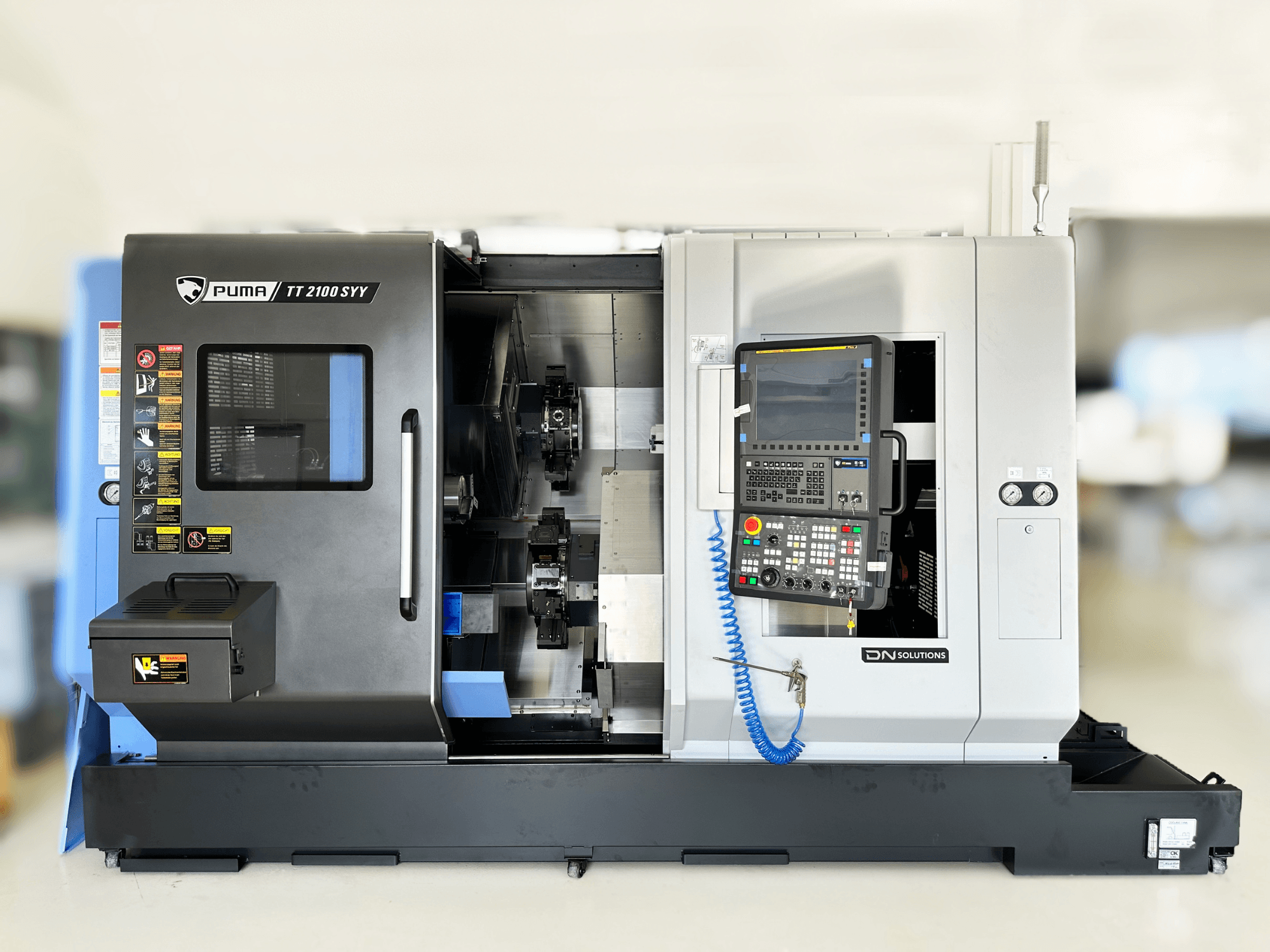 Soustružnické centrum DN SOLUTIONS PUMA TT2100SYY pohled zepředu, s ovládacím panelem a viditelnými vnitřními komponenty.