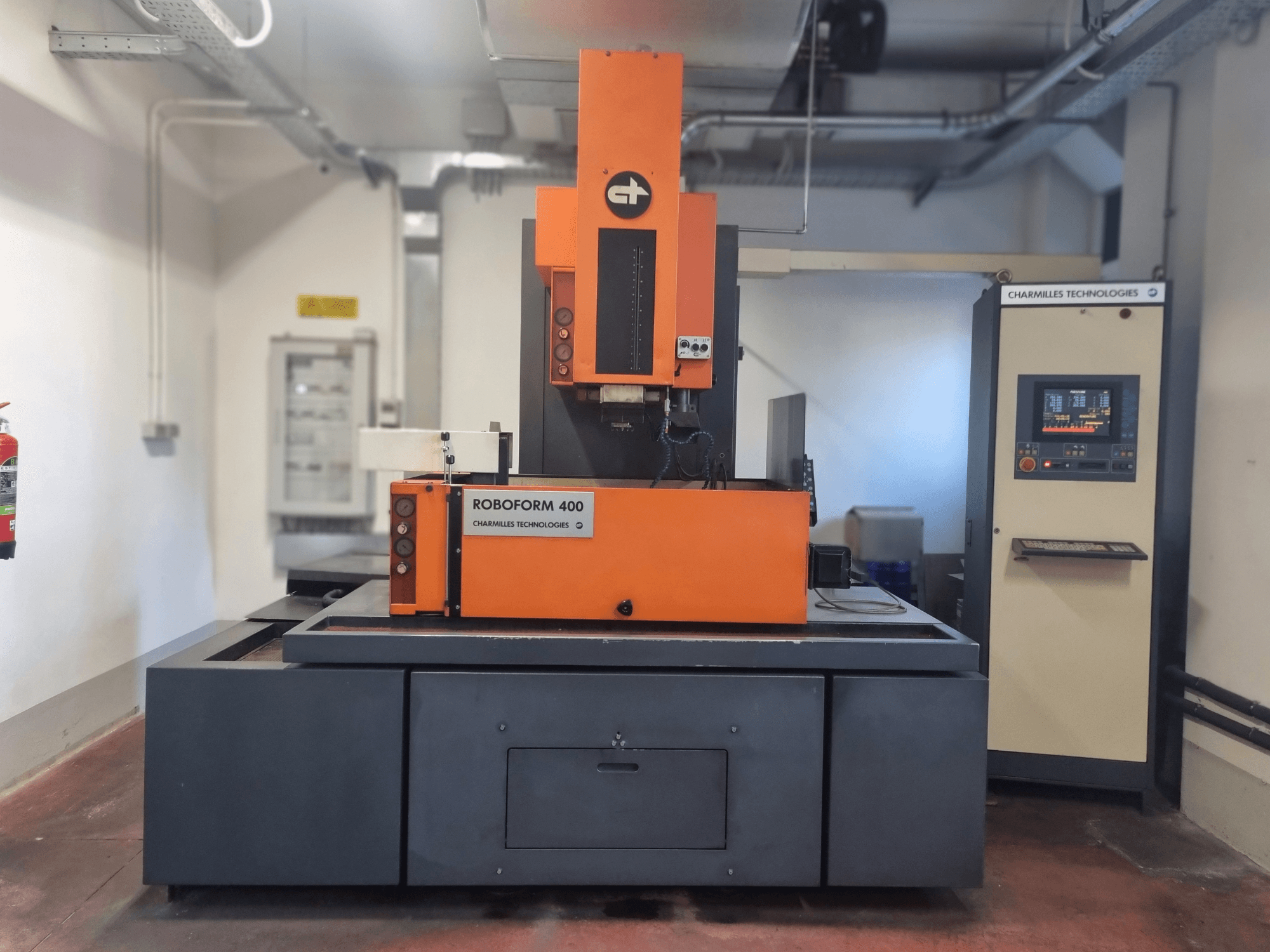 Stroj Roboforn 400 od společnosti Charmilles Technologies, pohled zepředu, oranžový a šedý design, viditelný digitální ovládací panel.