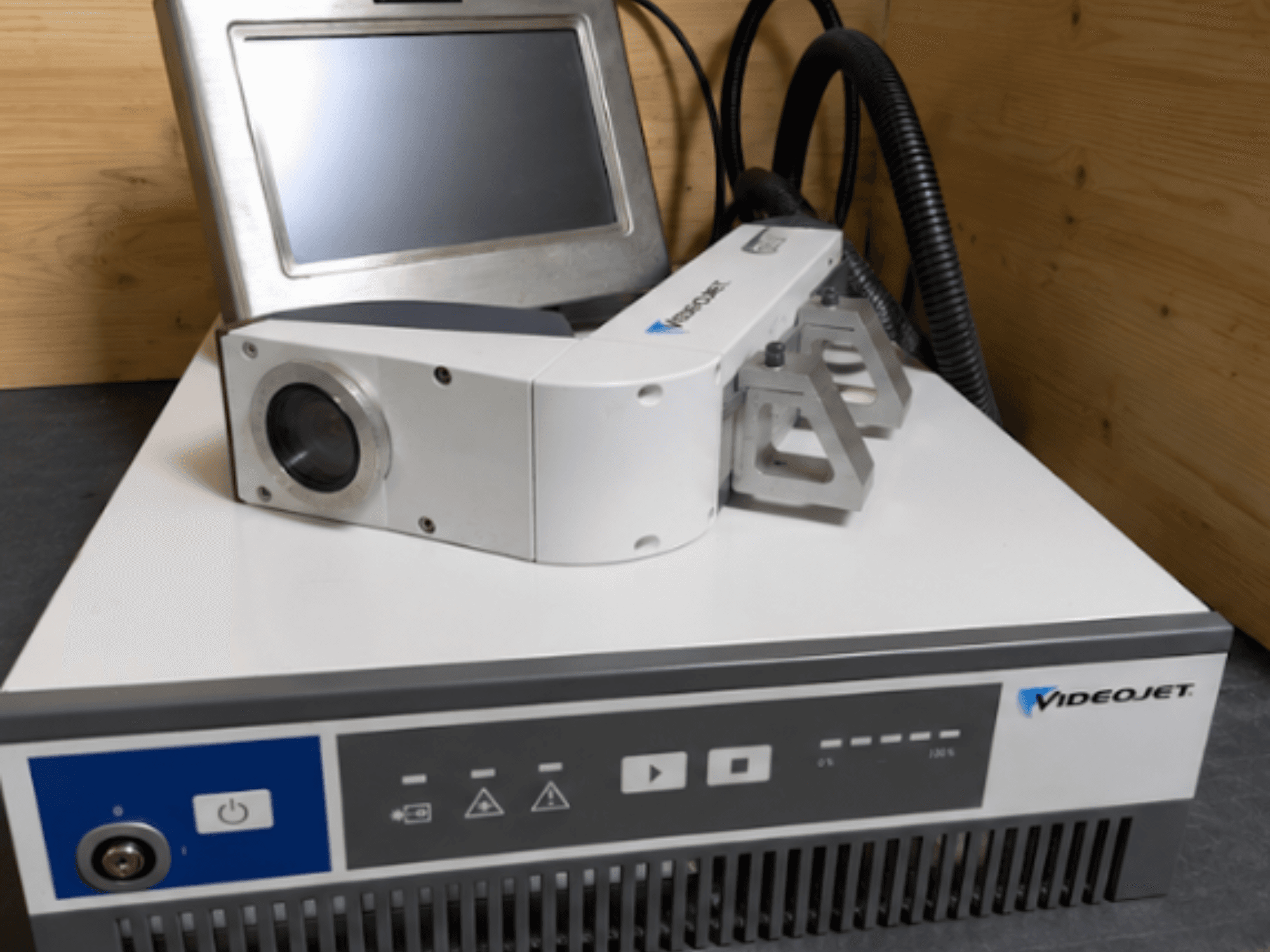 Laserový gravírovací stroj Videojet 7230, pohled zepředu, zobrazující ovládací panel a laserovou hlavu s objektivem a nástavcem.