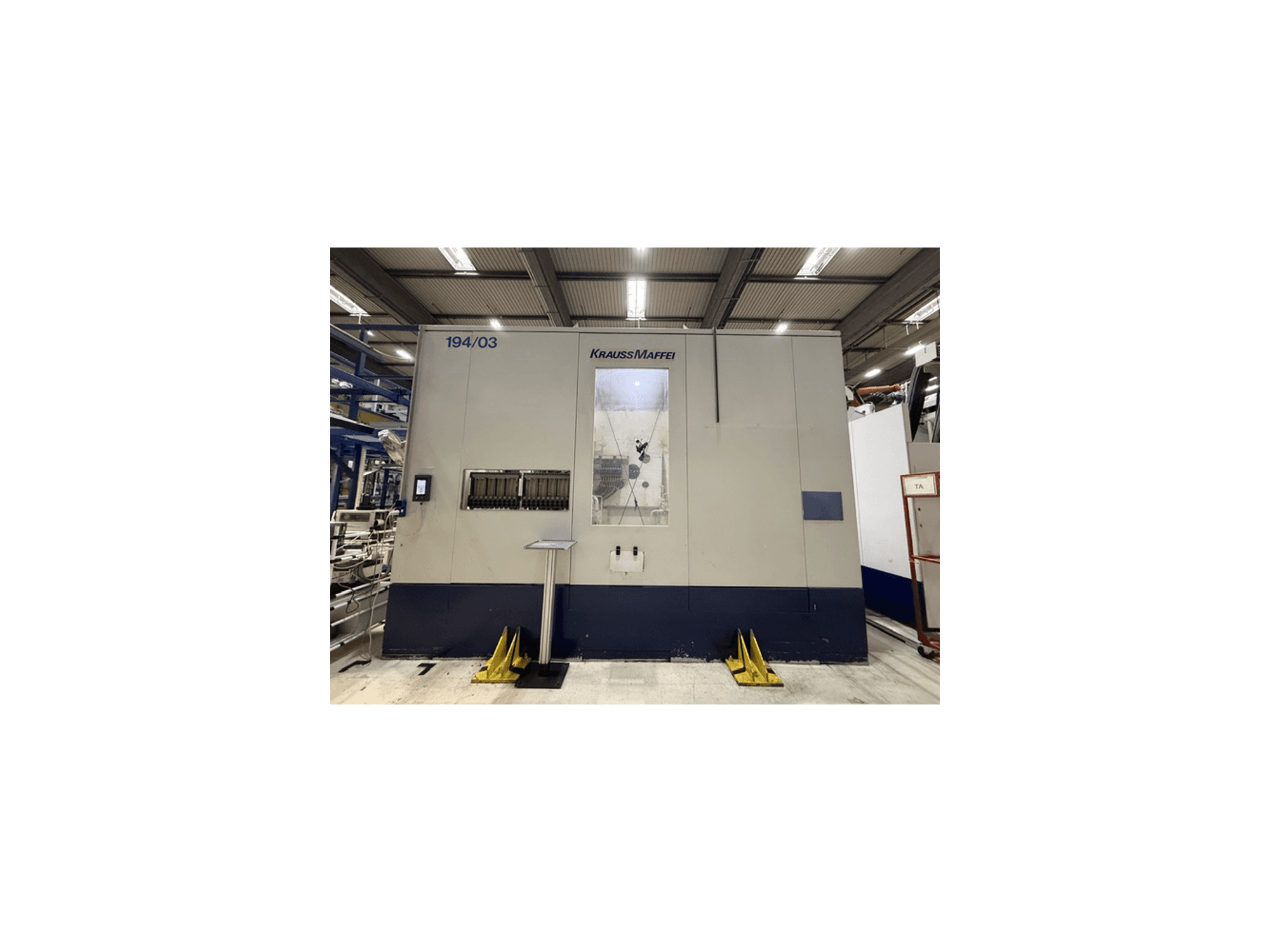 Hydraulický vstřikovací stroj Krauss Maffei 4000-24500 MC, pohled zepředu znázorňující ovládací panel a pracovní prostor.