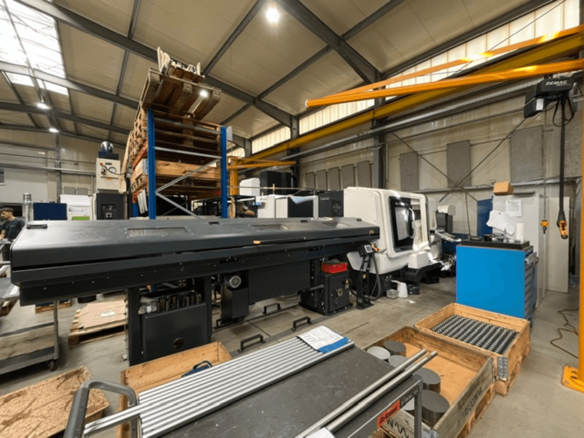 Horizontální soustruh DMG MORI MORI NLX 2500/700 SY v továrním prostředí, pohled z boku, s viditelnými nástroji a paletami.