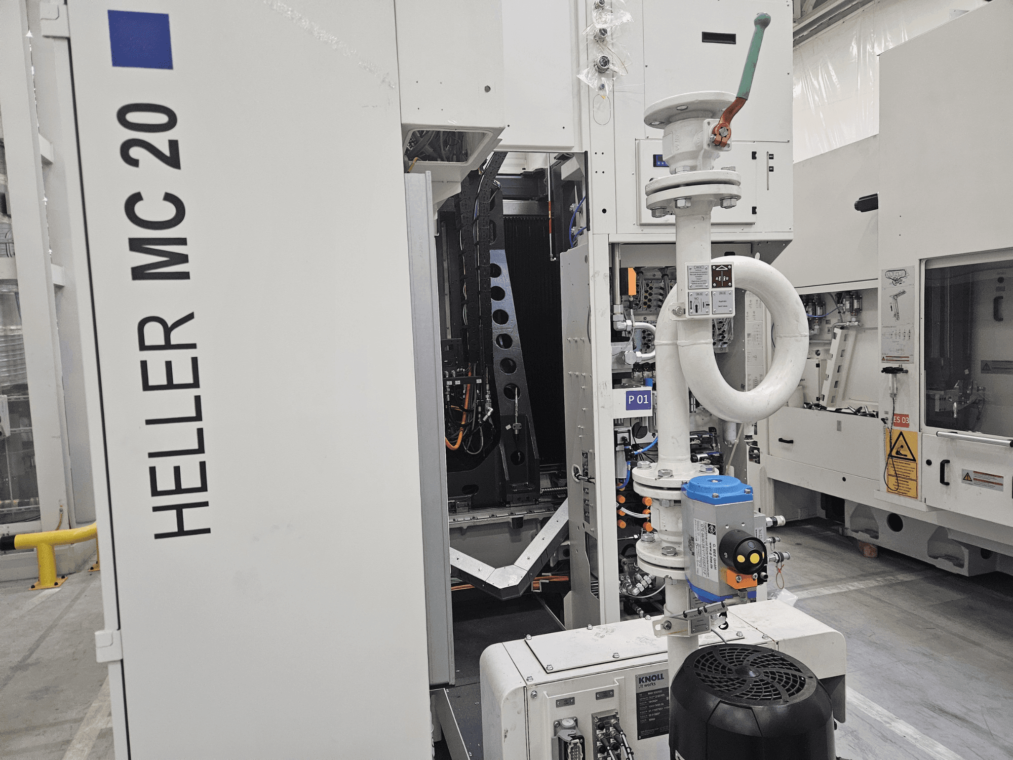 Stroj Heller MC 20 v továrním prostředí, ukázka ovládacího panelu a mechanických součástí z bočního pohledu.