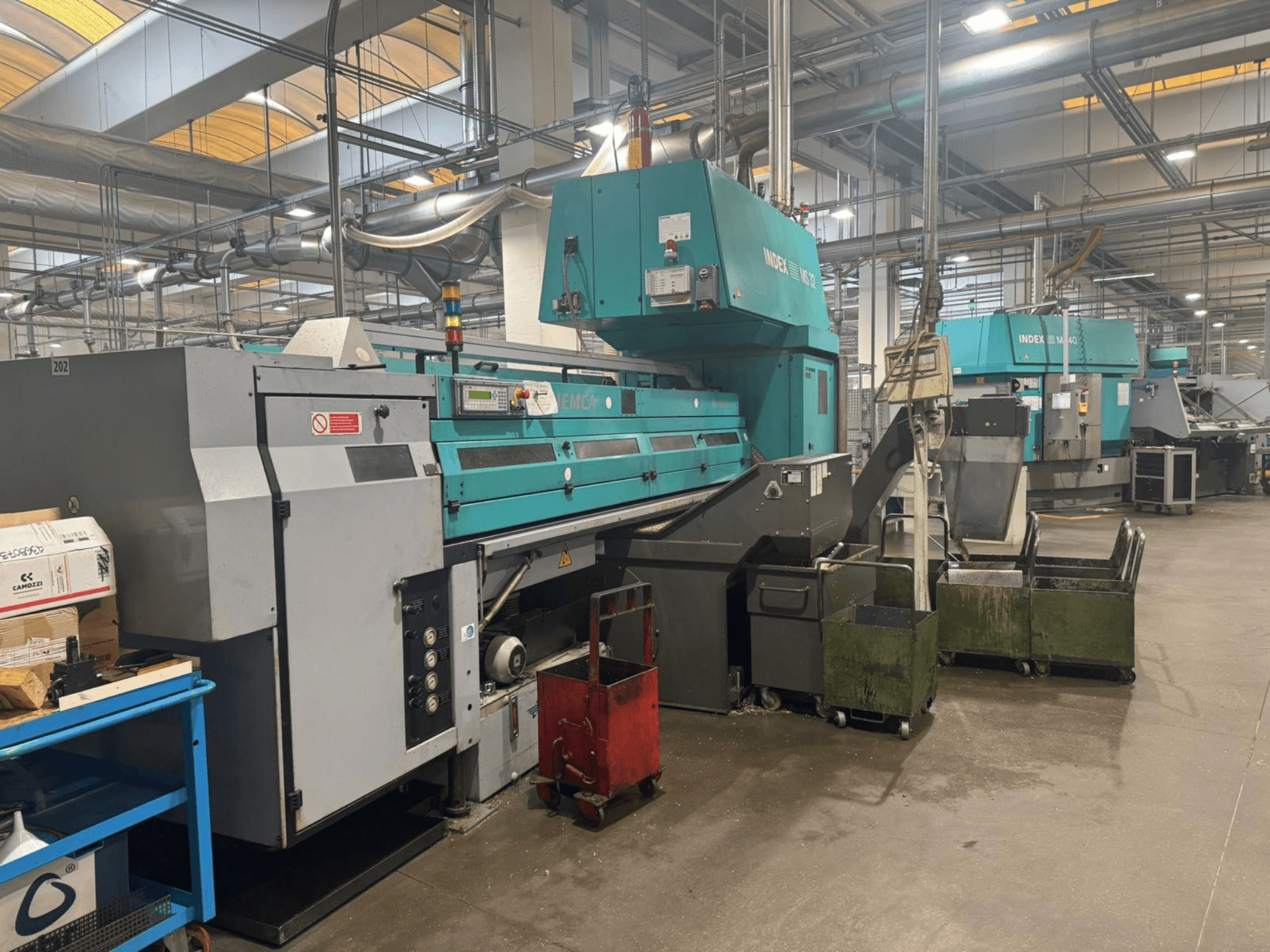 Vícevřetenový soustruh INDEX MS32C, pohled zepředu na ovládací prvky a pracovní prostor v dílně.