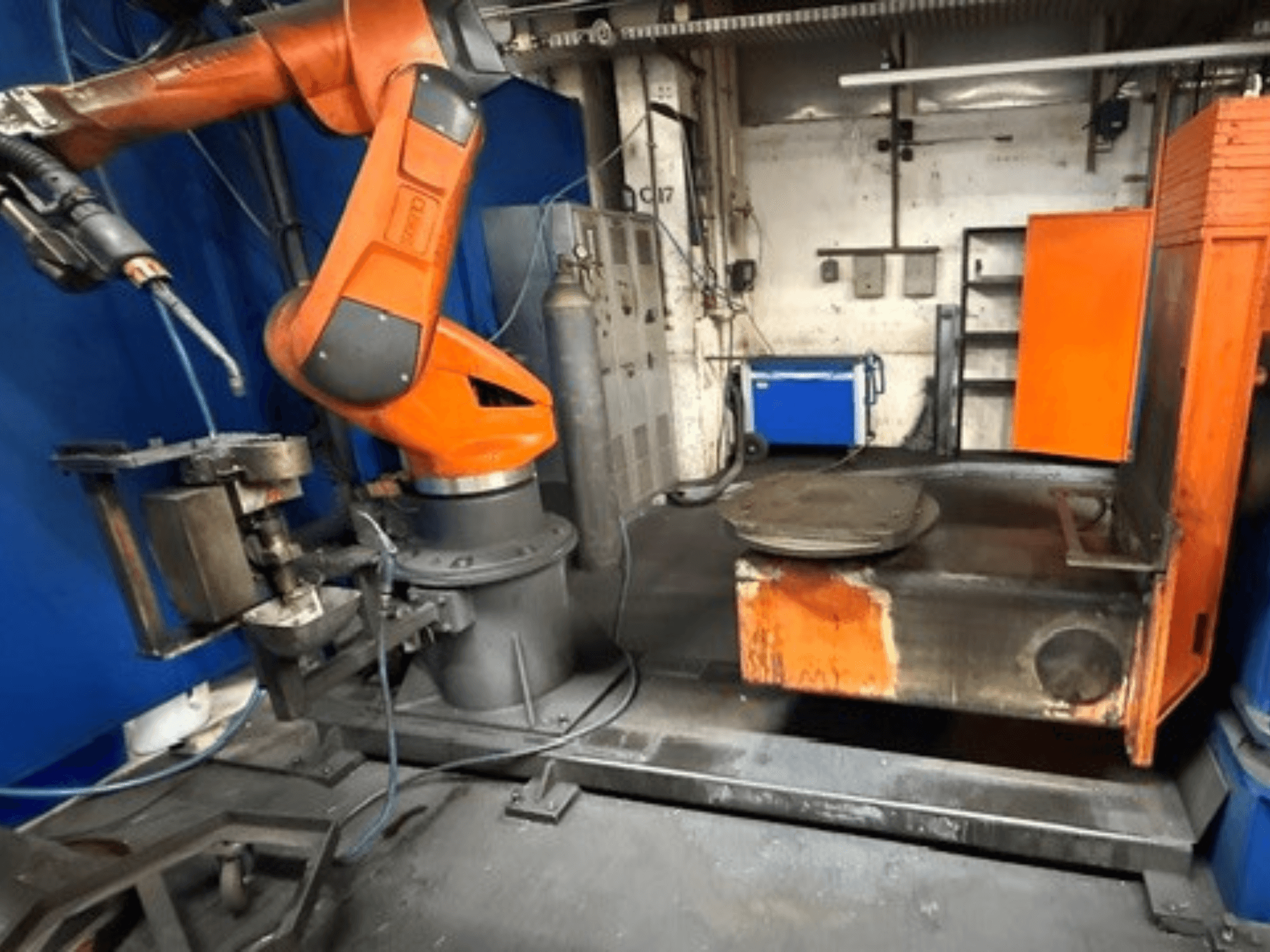 Svařovací robot CLOOS C50 v čelním pohledu, s oranžovým robotickým ramenem a kovovým pracovním stolem.