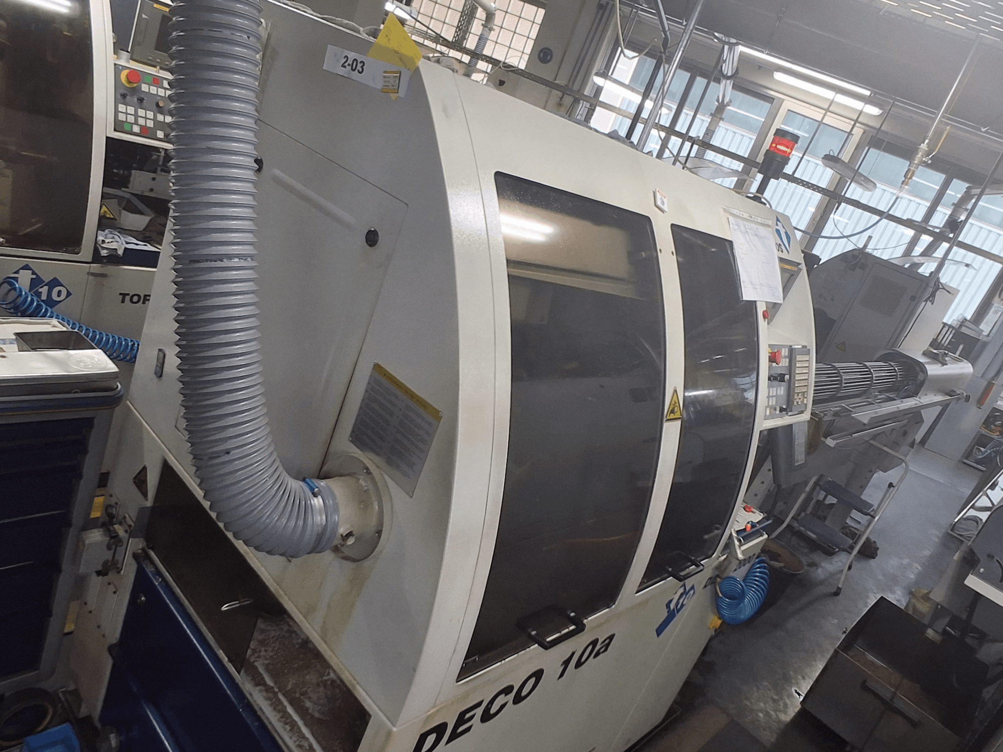 Stroj DECO 10a z čelního pohledu; viditelný velký ovládací panel, potrubí a provozní nálepky.