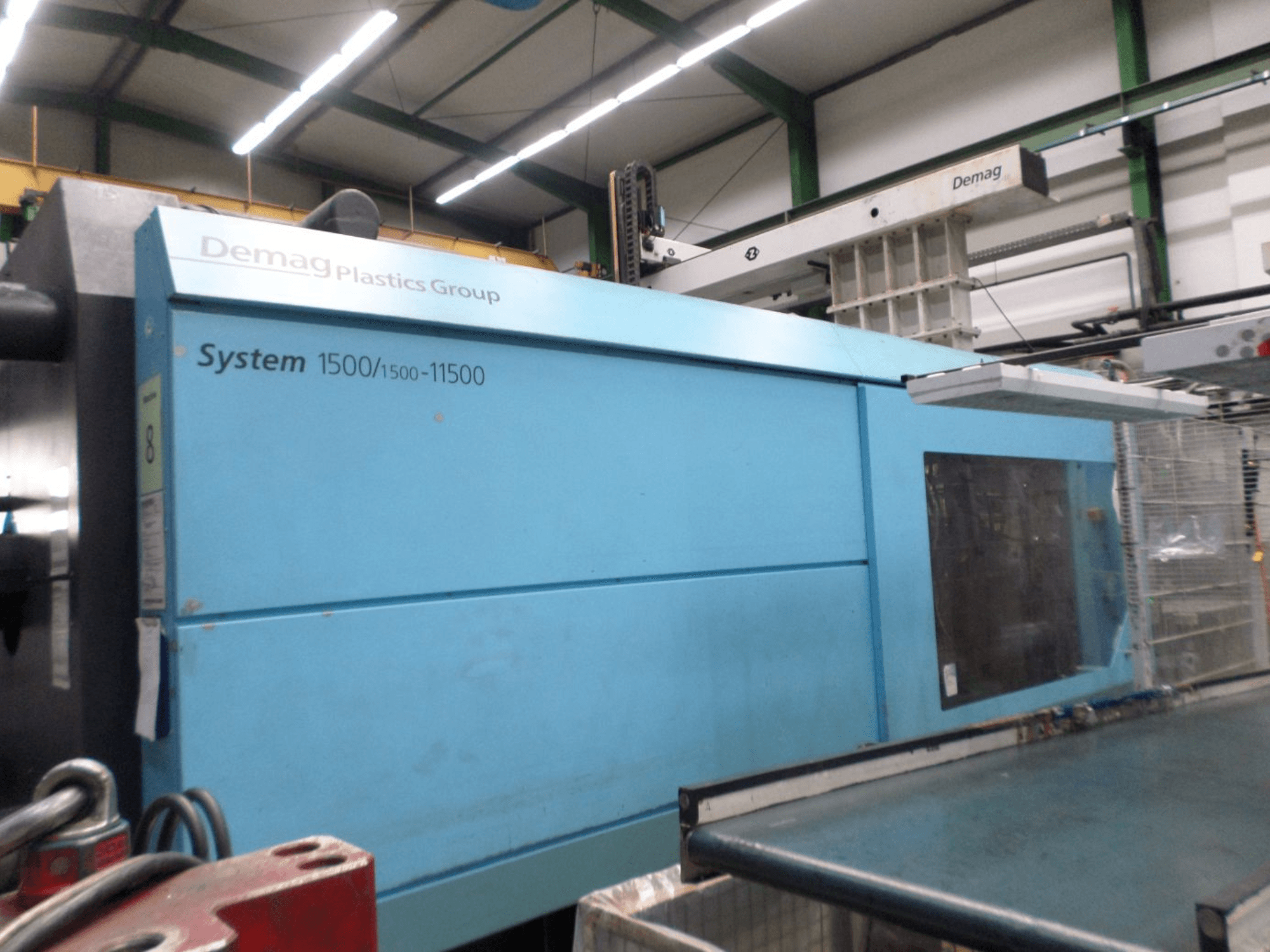Hydraulický vstřikovací stroj Demag D 650 v modré barvě, boční pohled znázorňující štítek „System 1500/1500-11500“ a pracovní prostor.