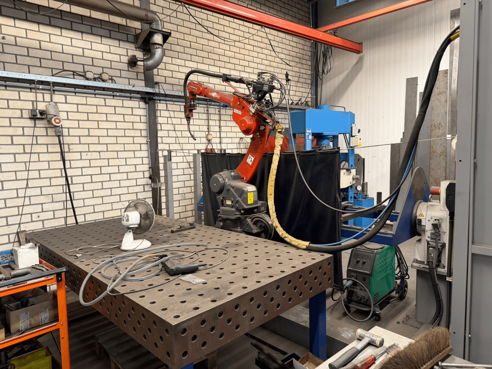 Pohled zepředu na svařovací robot PANASONIC TA-1800 na pracovní stanici s viditelným ventilátorem a svařovacím zařízením.