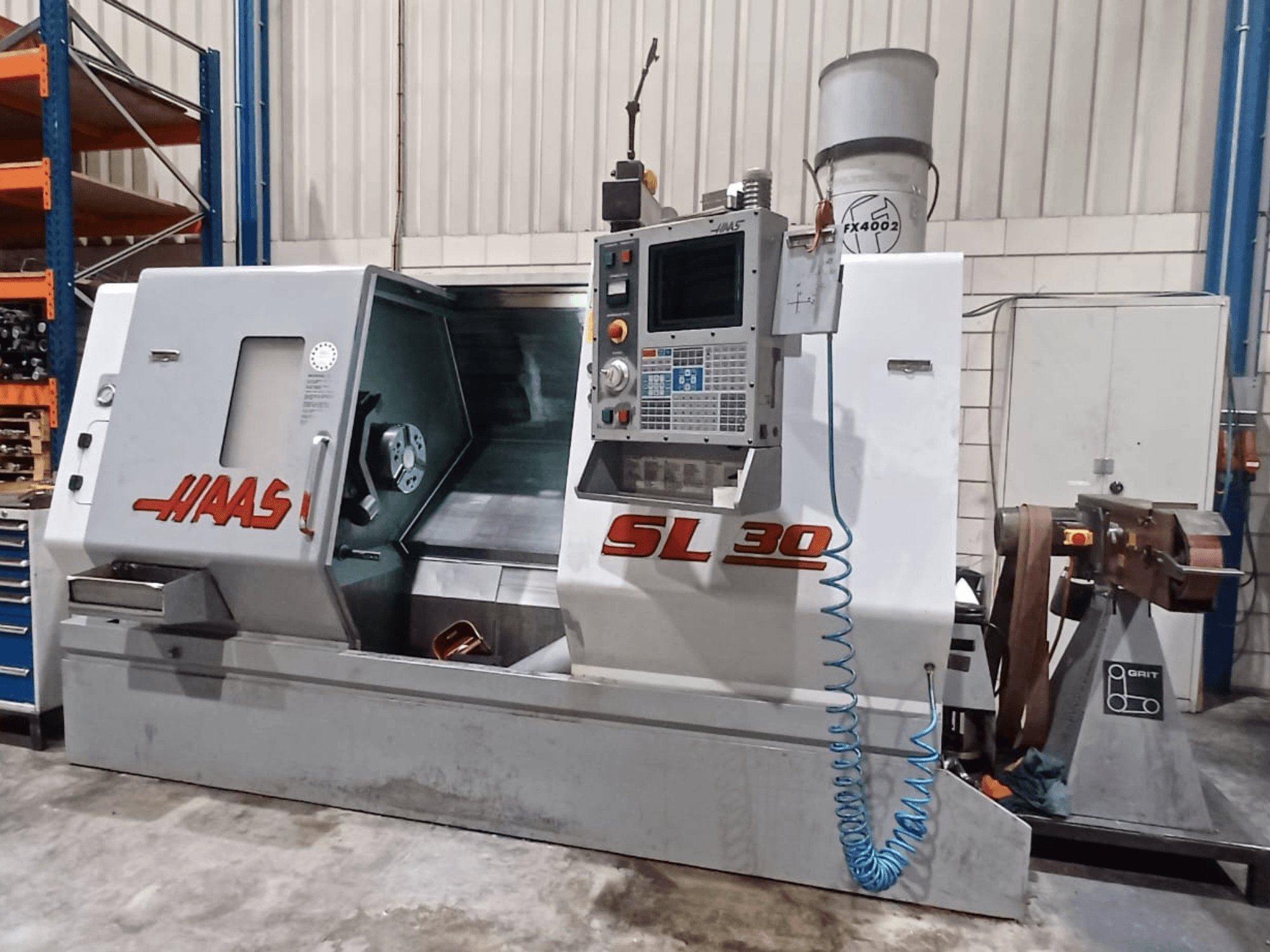 CNC soustruh Haas SL 30 v bočním pohledu, který ukazuje ovládací panel, obráběcí plochu a integrovaný chladicí systém pro obrábění kovů.